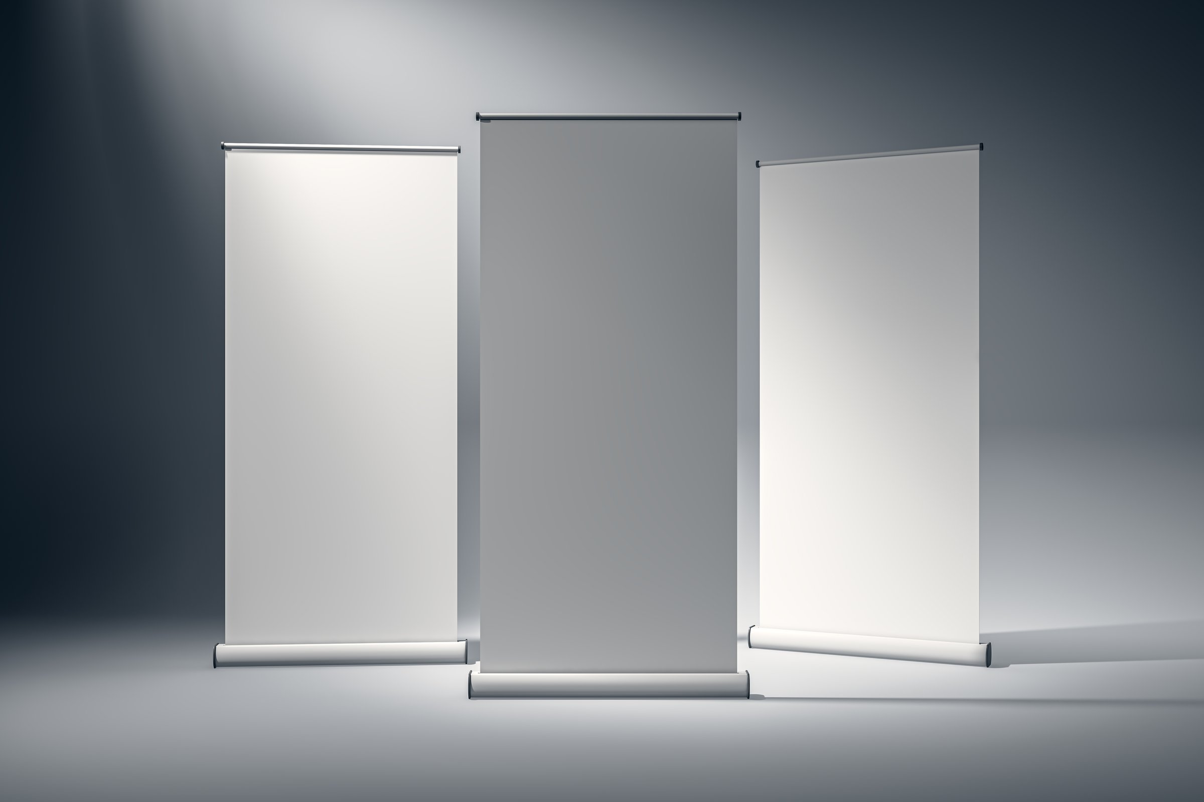 Three blank roll-up banners standing vertically in a studio with a grey background. Ideal for mockup designs, logos, and promotional events. 3D Rendering