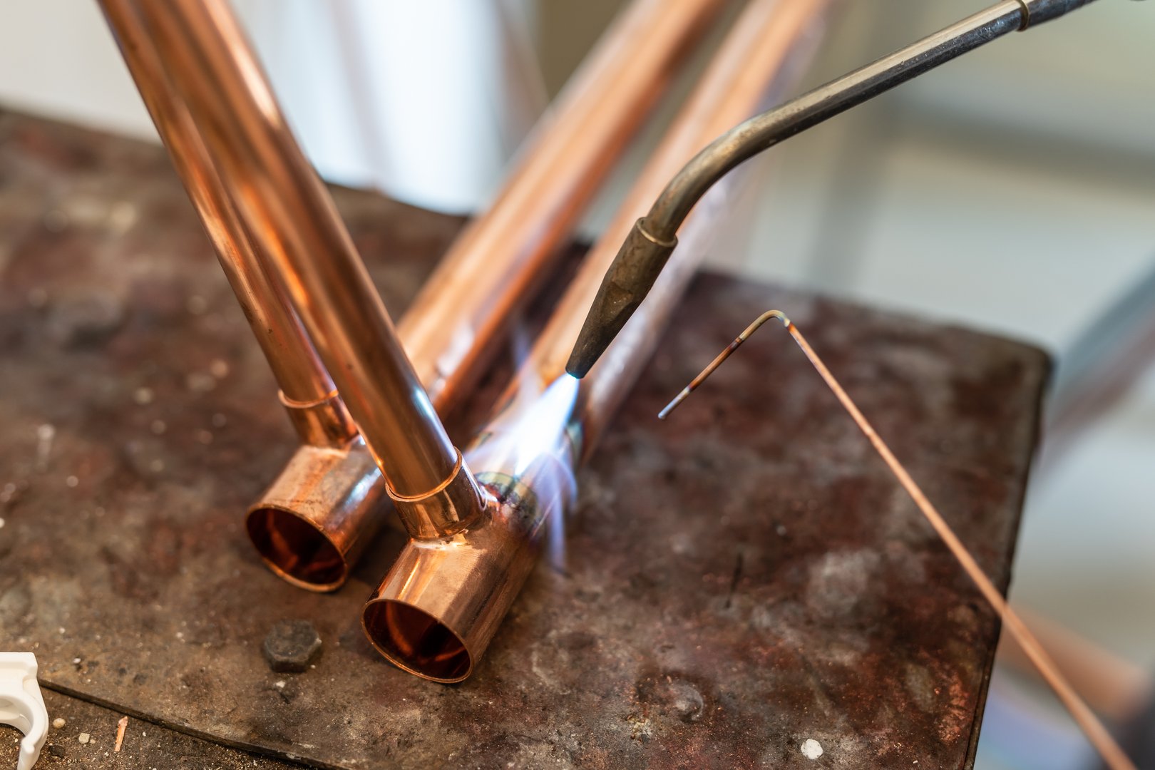 Close up on hands of unknown industrial worker plumber with central heating copper pipes welding using gas torch or blowtorch at work