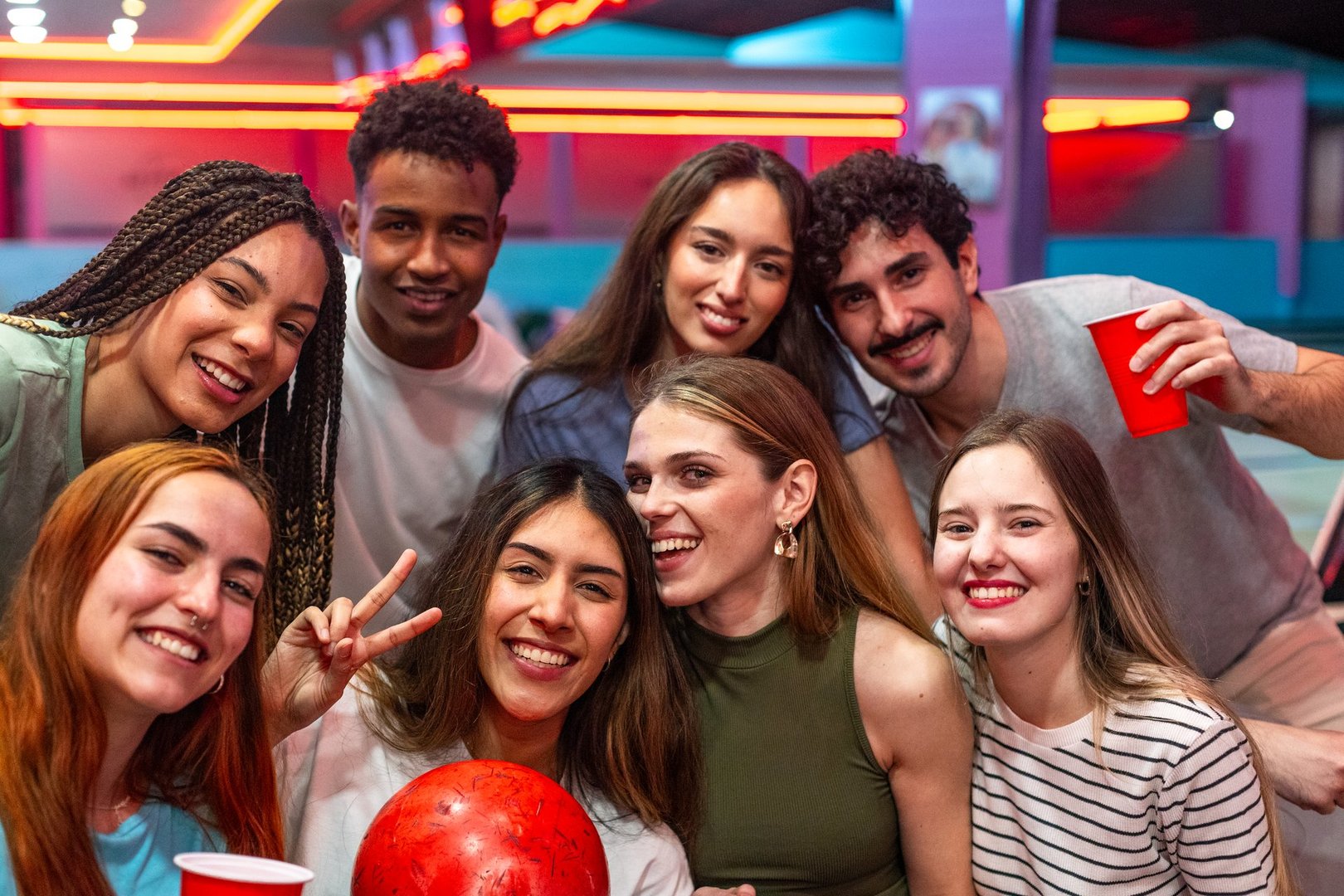 Happy multi ethnic friends enjoying laughter and fun while bowling together at the lively alley, creating unforgettable memories