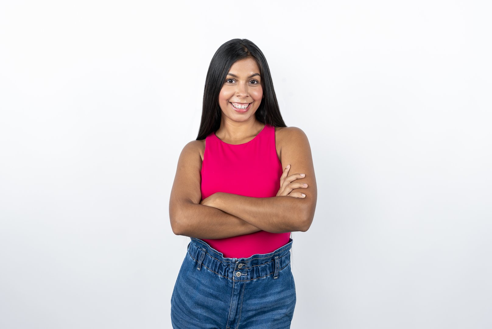 Portrait of a Mexican Woman in Pink Shirt and Blue Jeans Smiles at the Camera with Arms Crossed. Concept of Positivity