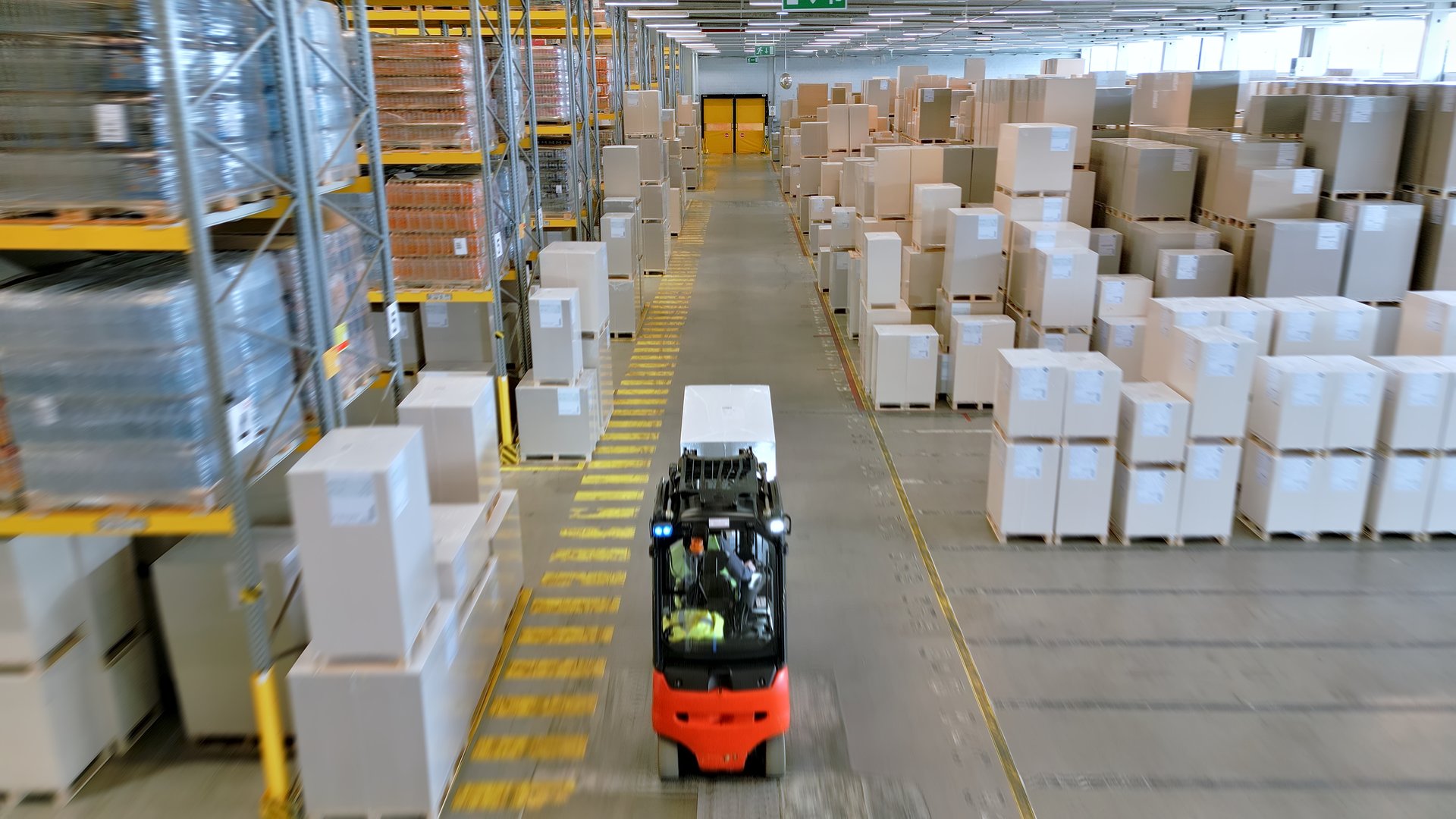A forklift navigates the aisles of a vast warehouse, highlighting the efficiency of global supply chain logistics and the dedication of warehouse workers.