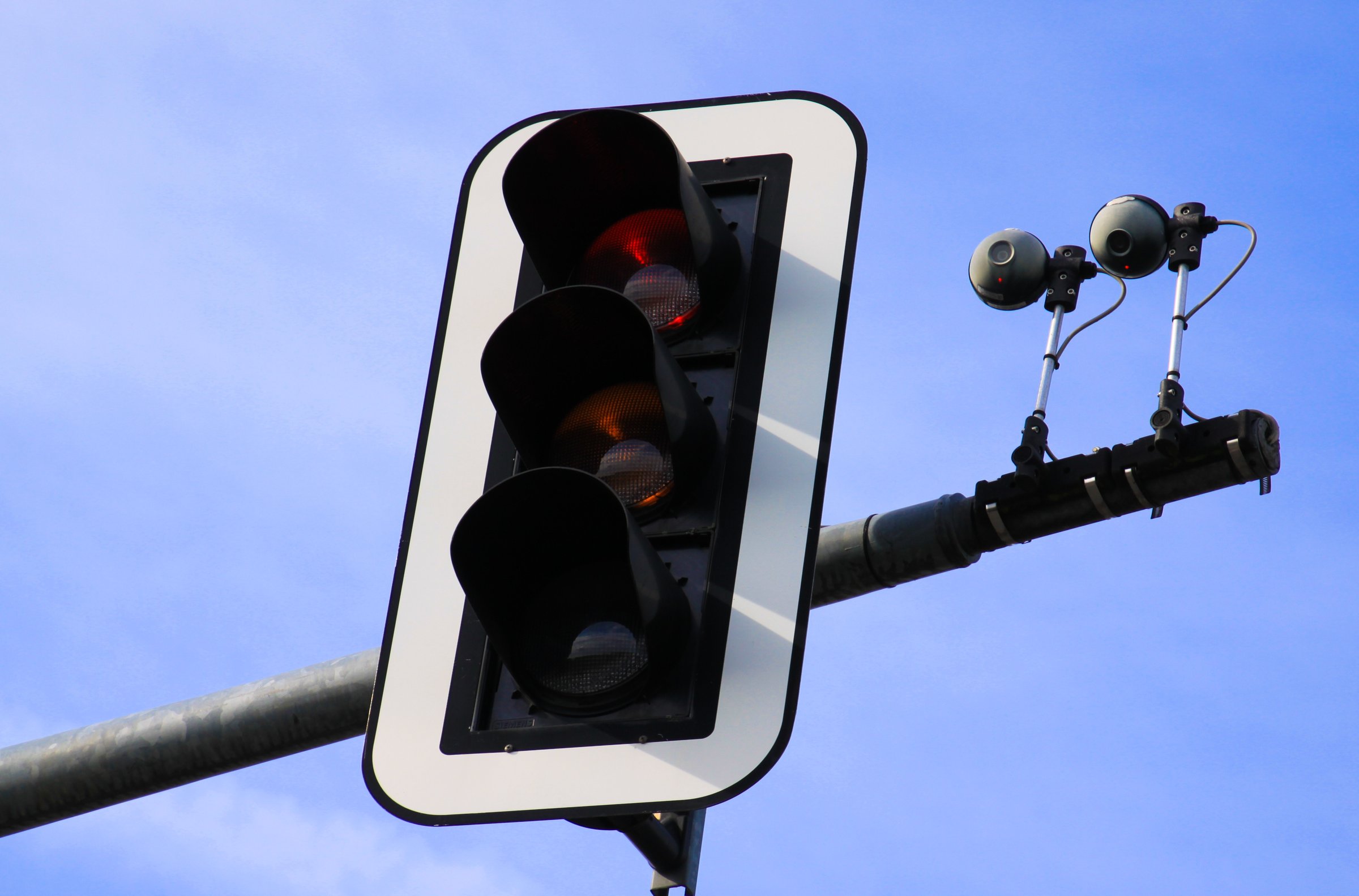 View on isolated radar based cameras and detector with red traffic light against blue sky