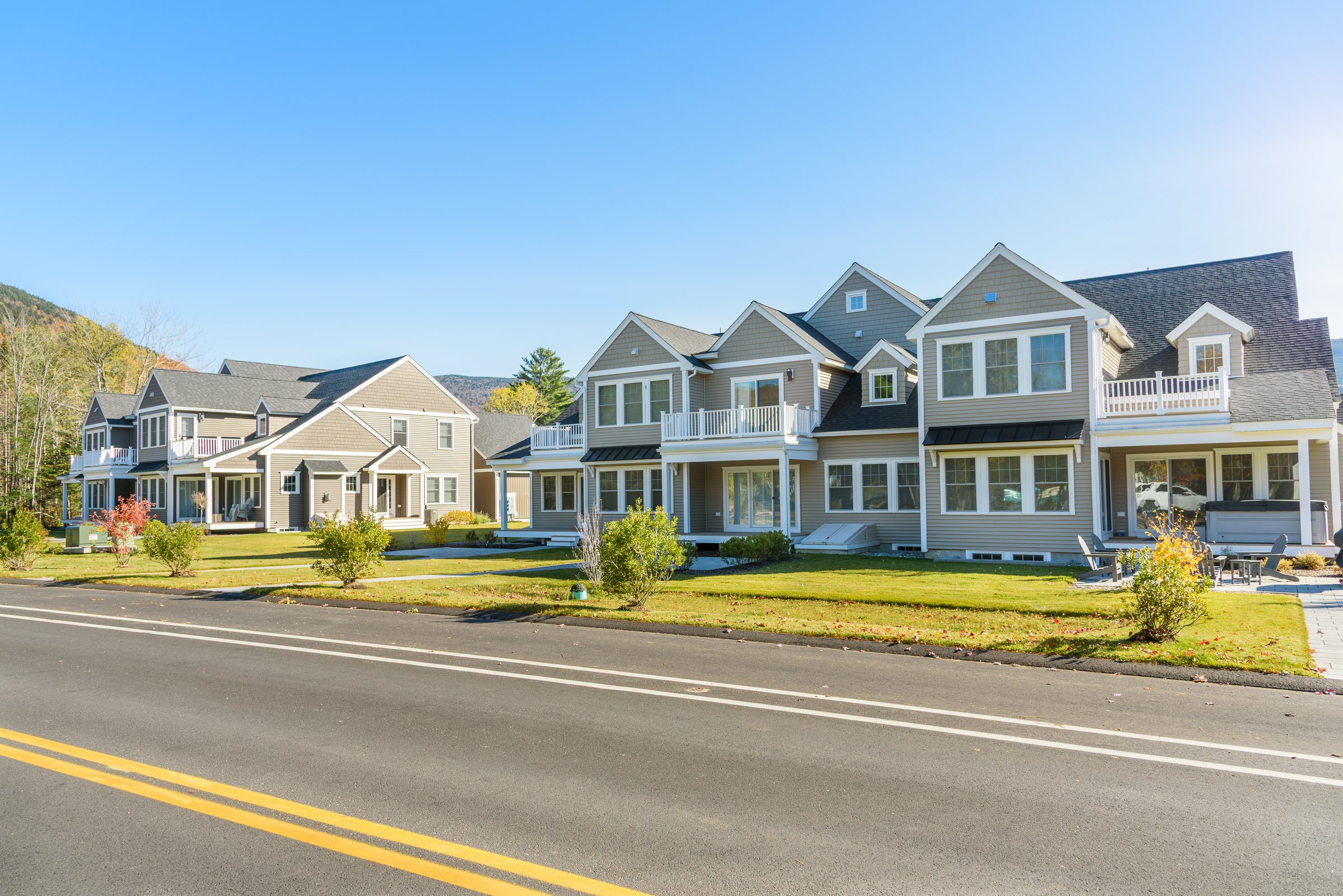 Modern row houses along a road in a new housing development in mountain village on a clear autumn day. Waterville valley, NH, USA.