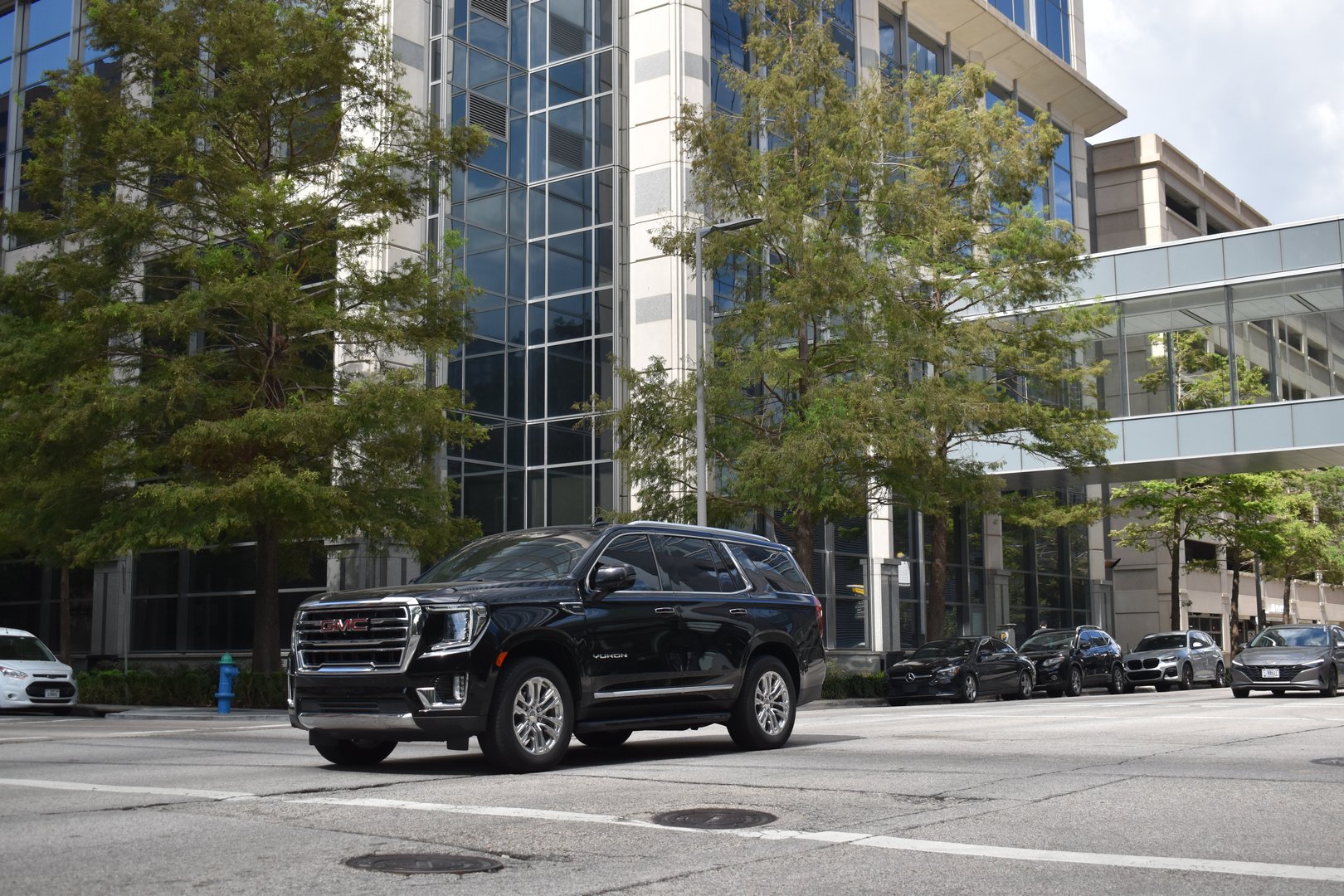 Houston, TX USA - A portrait of a black GMC Yukon XL Denali luxury SUV cruising in a downtown district