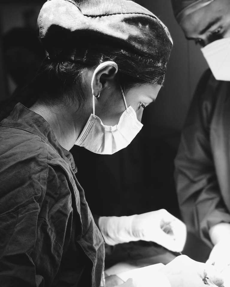 Two surgeons wearing masks and gloves performing a surgical procedure in an operating room.