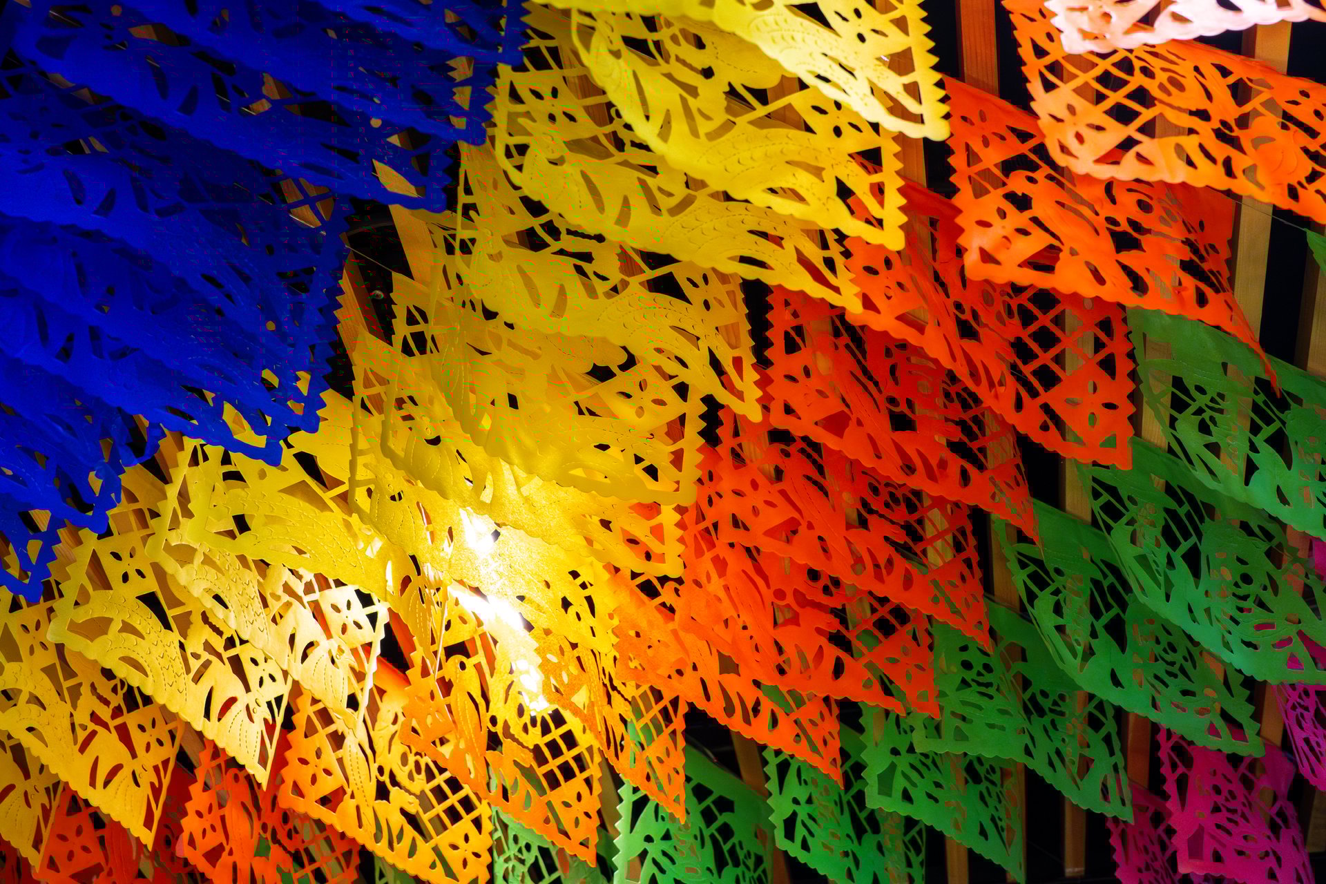 A vibrant and lively display of colorful paper flags arranged in a way that creates a sense of movement and energy. Day of the Dead celebration in Mexico, papel picado crafts, offerings, La Catrina