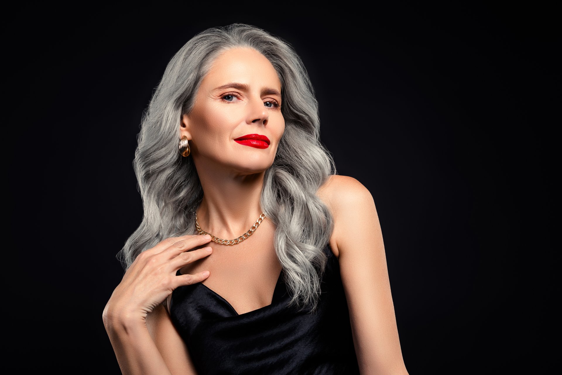 Sophisticated and stylish image of a mature woman with gray hair wearing a glamorous black dress, exuding beauty and elegance. Suitable for concepts like fashion, age, and timeless charm.