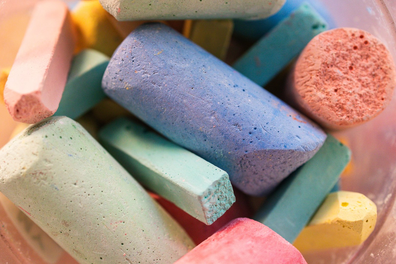 A collection of vibrant chalk pieces in various colors and shapes rests together in a container, ready for summer outdoor art activities and creative projects.