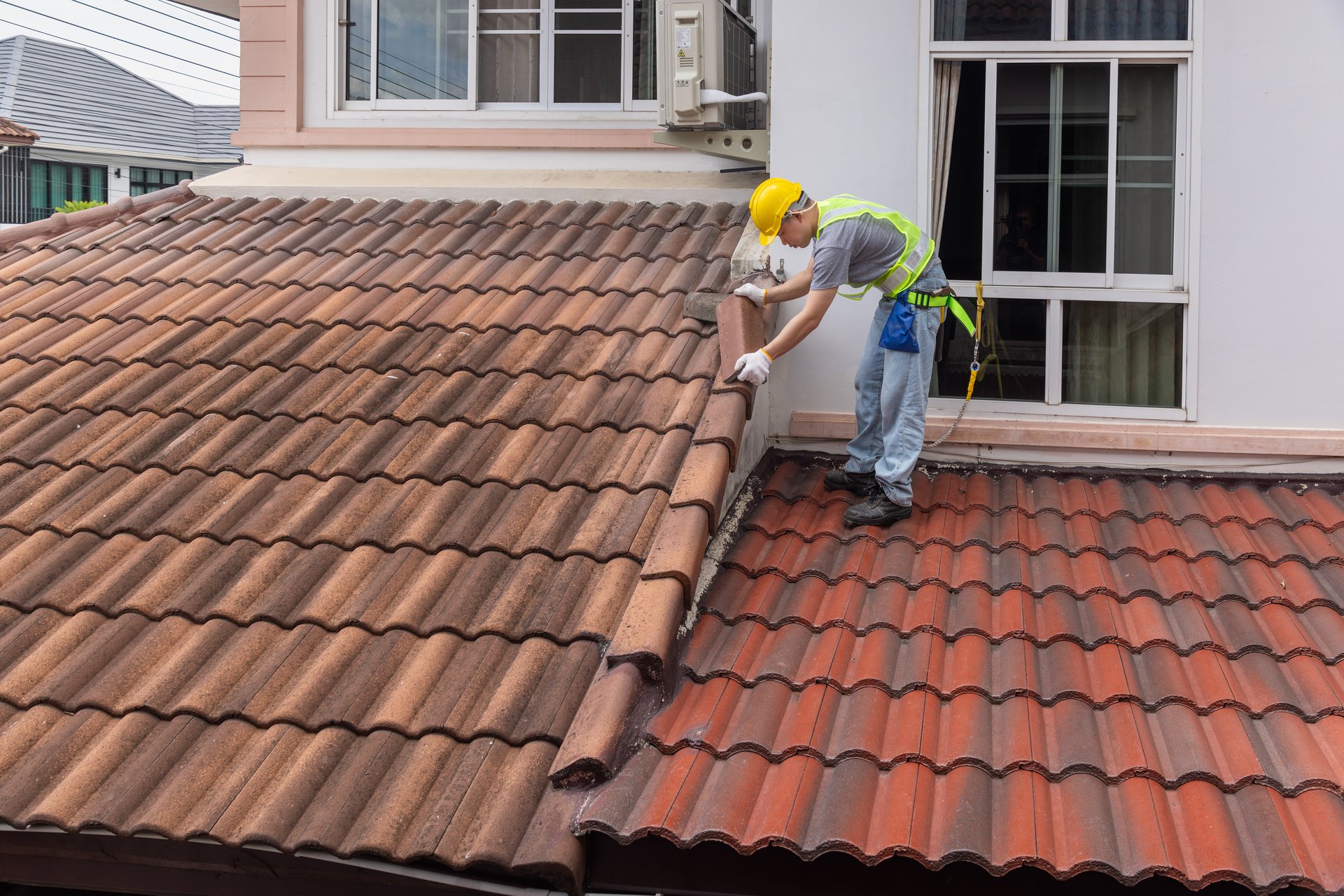 Worker fixing eaves and tiles of the old roof.
