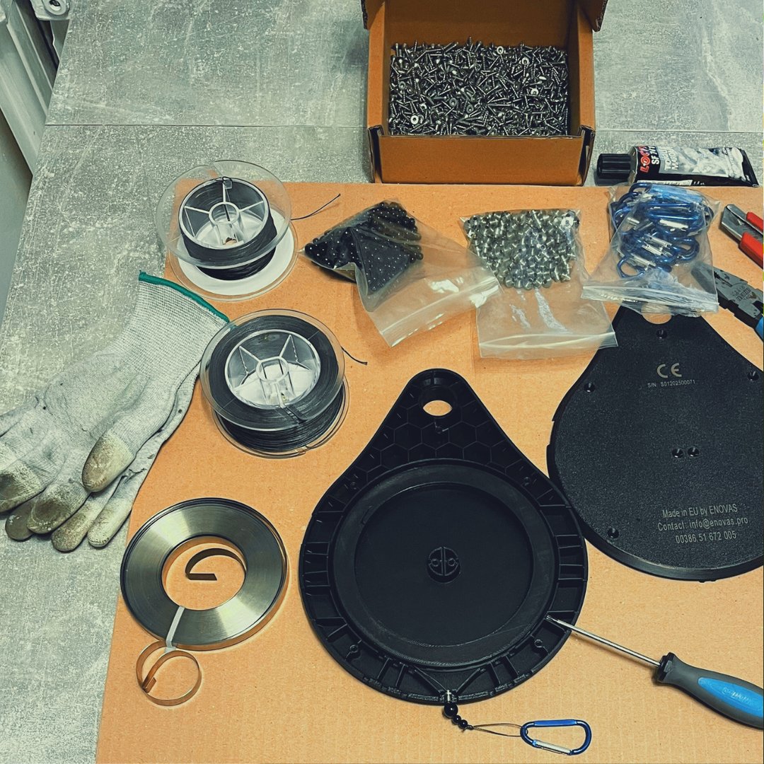 Assorted tools and materials on a table, including gloves, screws, a screwdriver, tape, and circular metal parts.