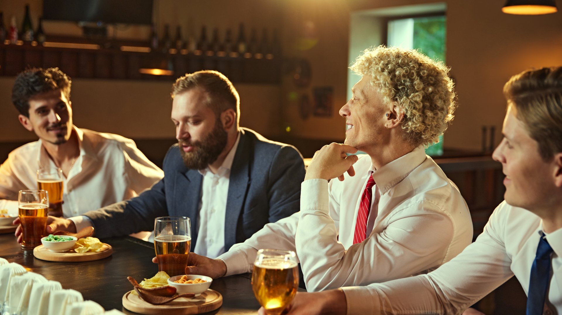 Casual and relaxed, group of colleagues enjoys evening, drink together, with warm glow of bar setting mood for unwinding. Concept of work-life balance, business and leisure, lifestyle. Ad.