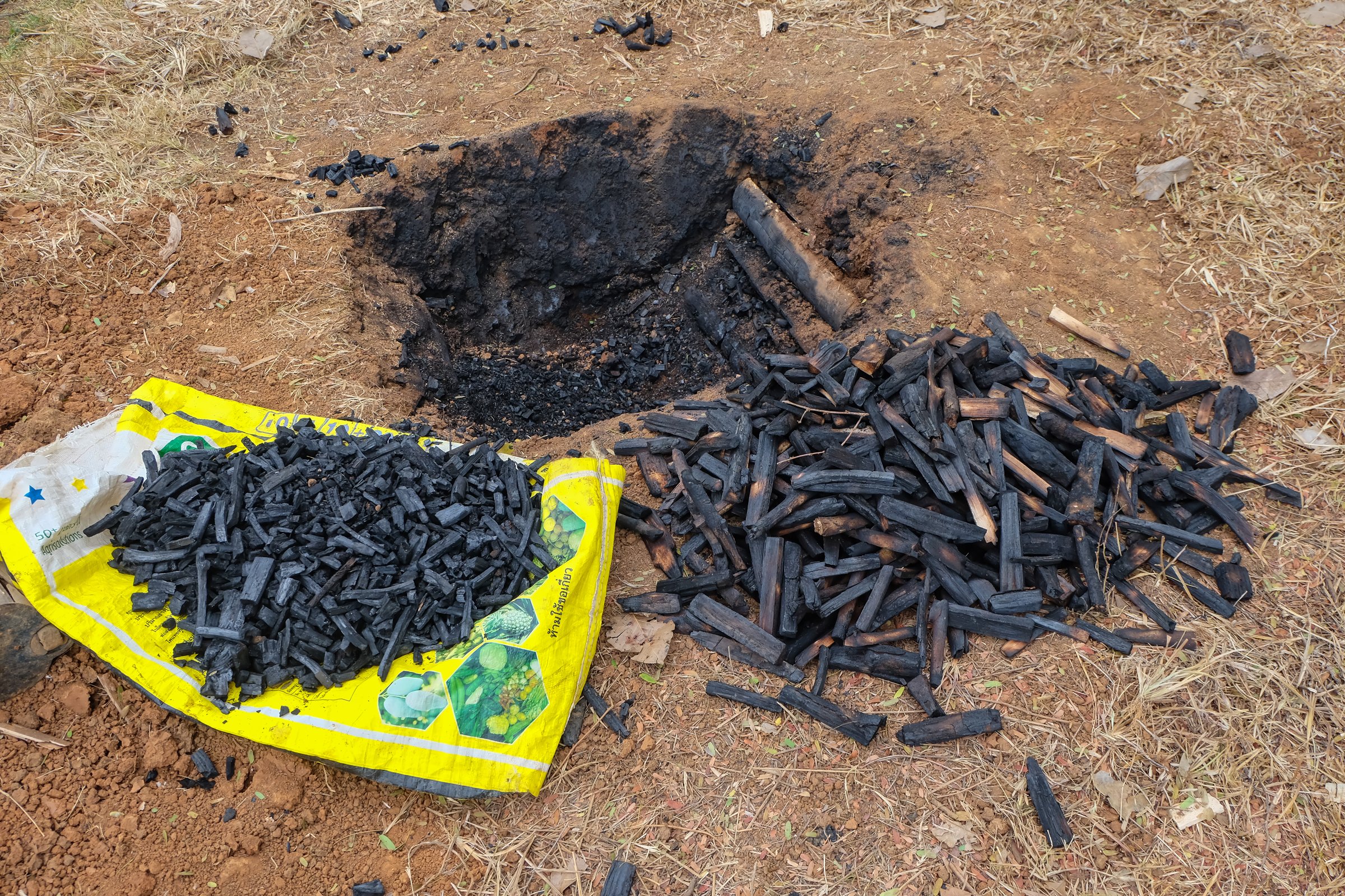 Tachileik, Myanmar - April 1 2017. Biochar pit and graded sticks (small and large)