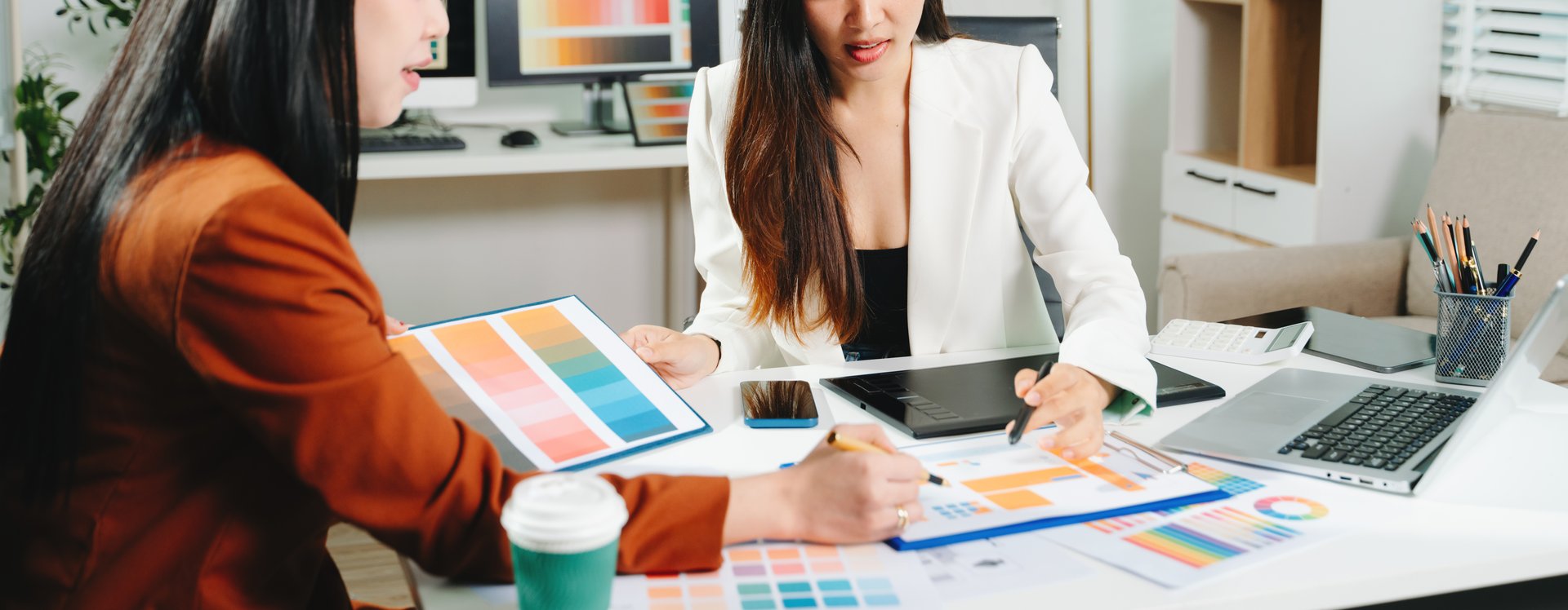 Two female designers collaborating on color palette and UX UI project in a modern creative office. Perfect for business, teamwork, and innovation themes.