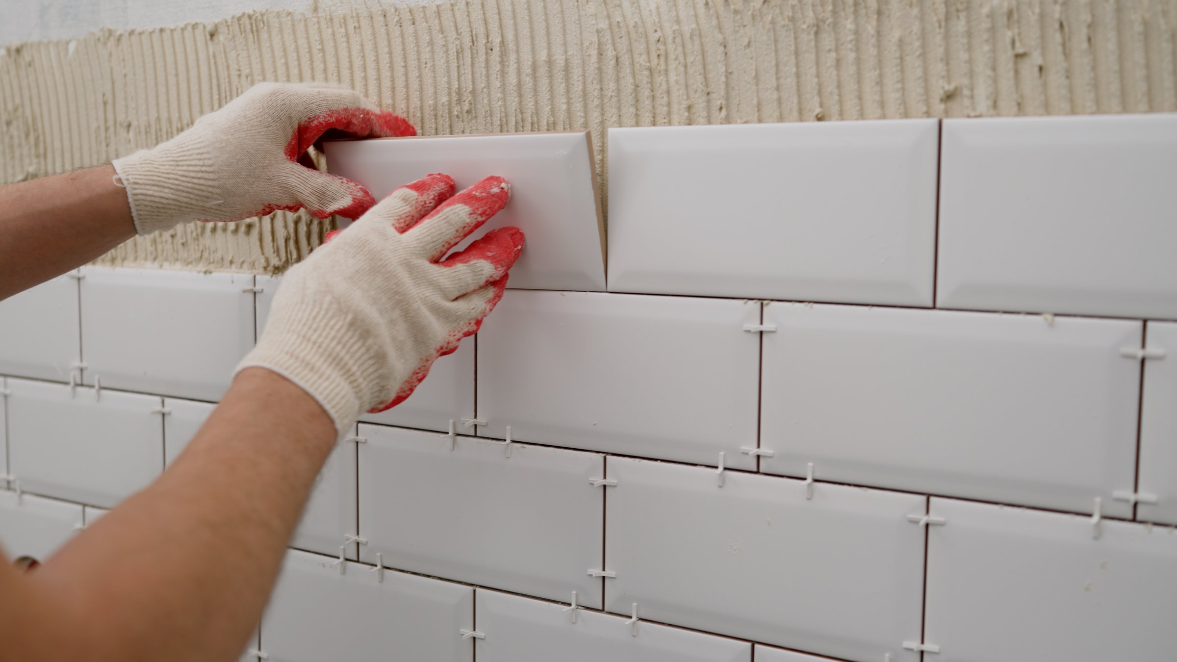 Laying backsplash tiles in the kitchen. Tile apron in the kitchen. White tiles, leveling clips, tile cement.