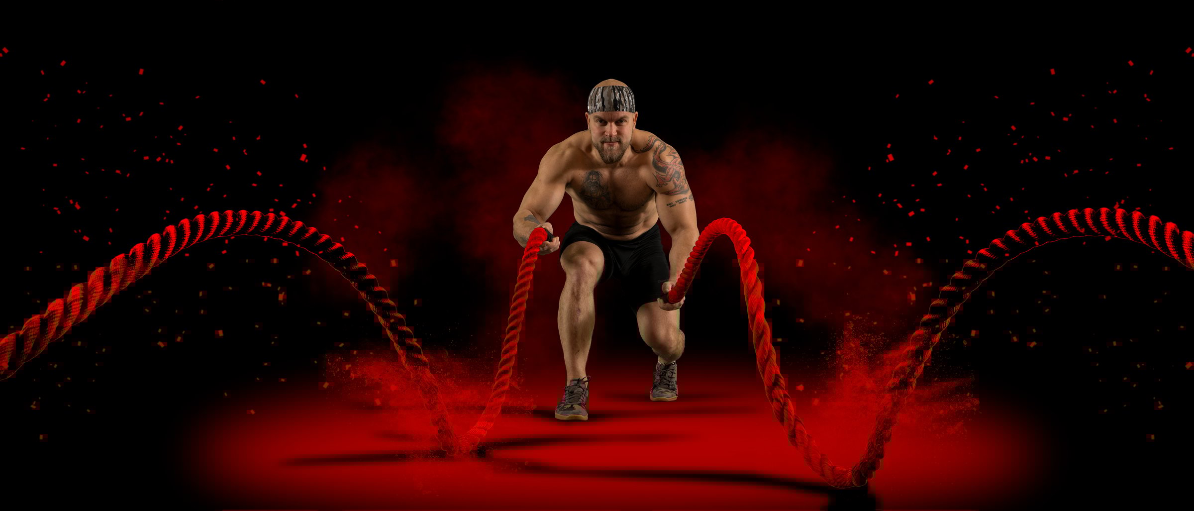 Muscular Man working out with battle ropes on dark
