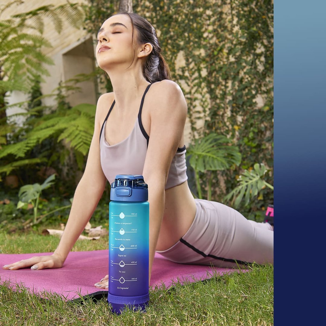 Woman doing yoga on a pink mat outside, with a blue gradient water bottle featuring motivational time markers in the foreground.