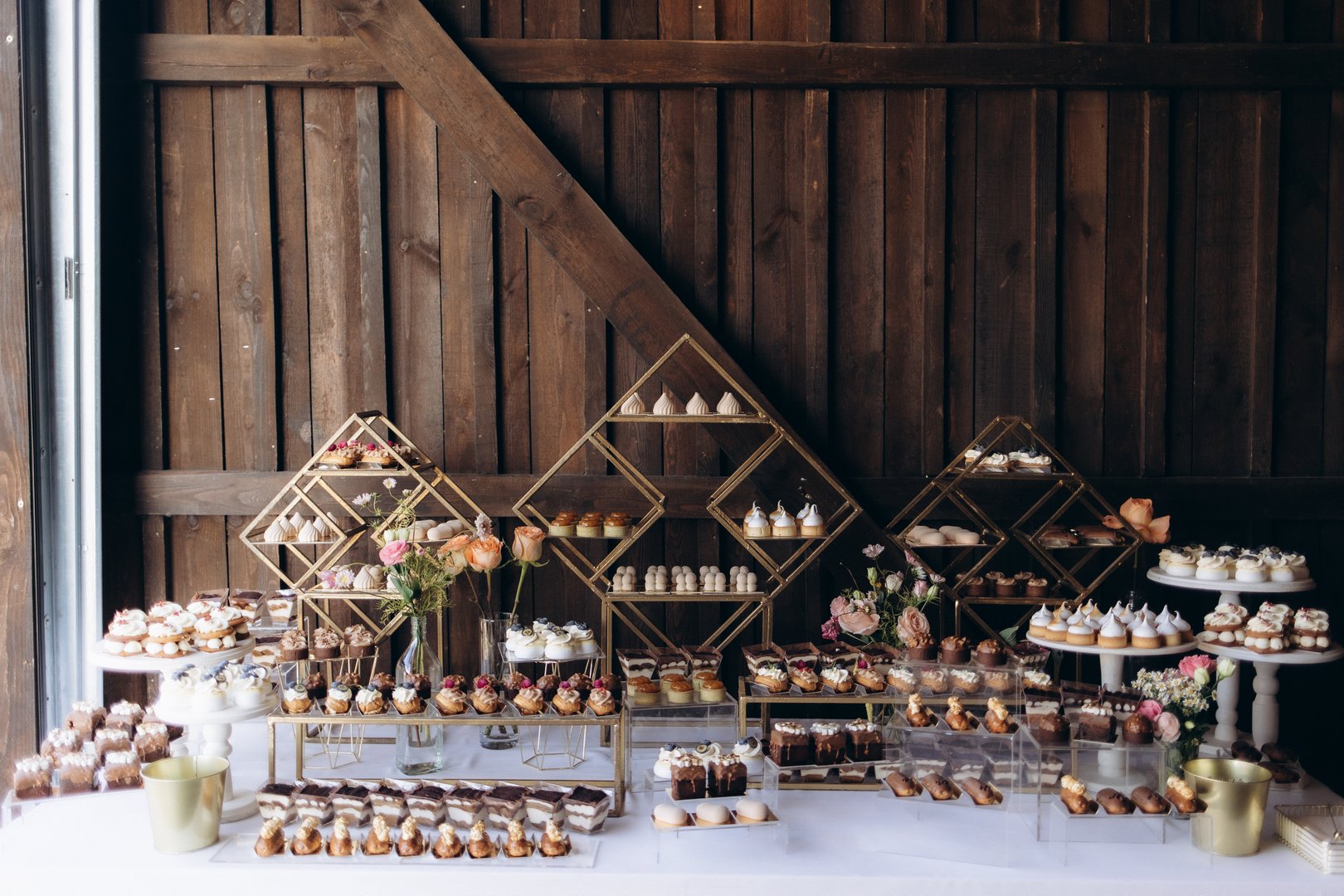A beautifully arranged dessert display featuring a variety of pastries and cakes, styled in a rustic setting, perfect for weddings, parties, and celebrations.