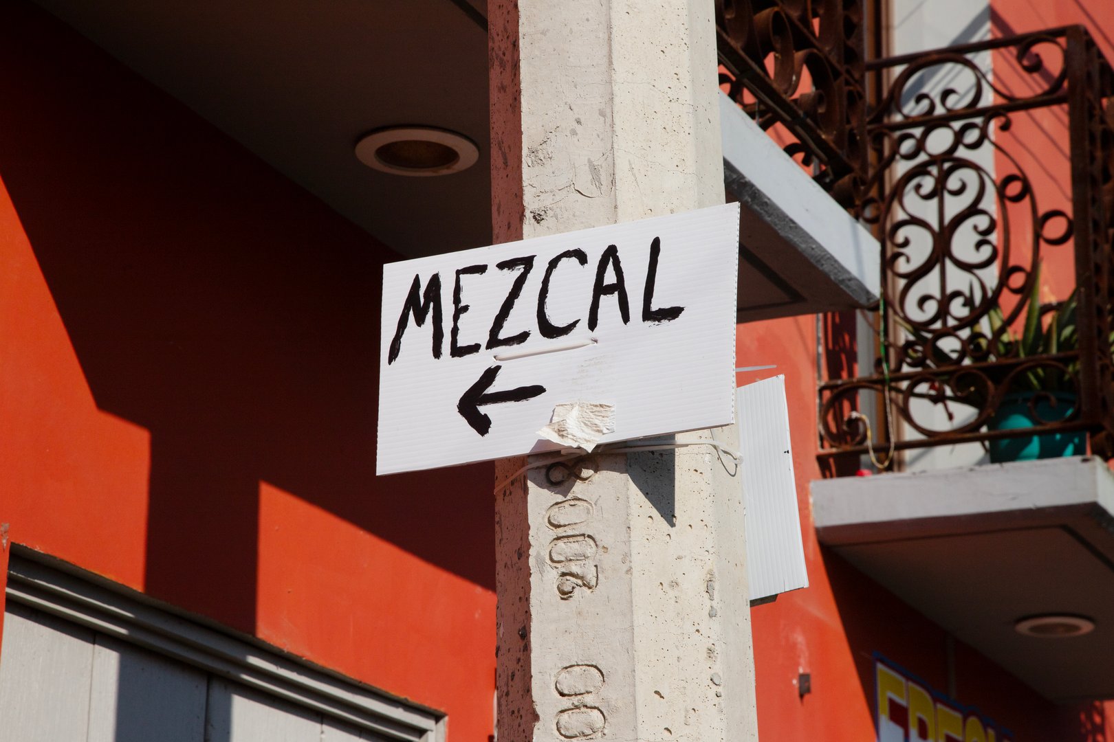 A white sign with the word mezcal written on it on a street in Oaxaca, Mexico.