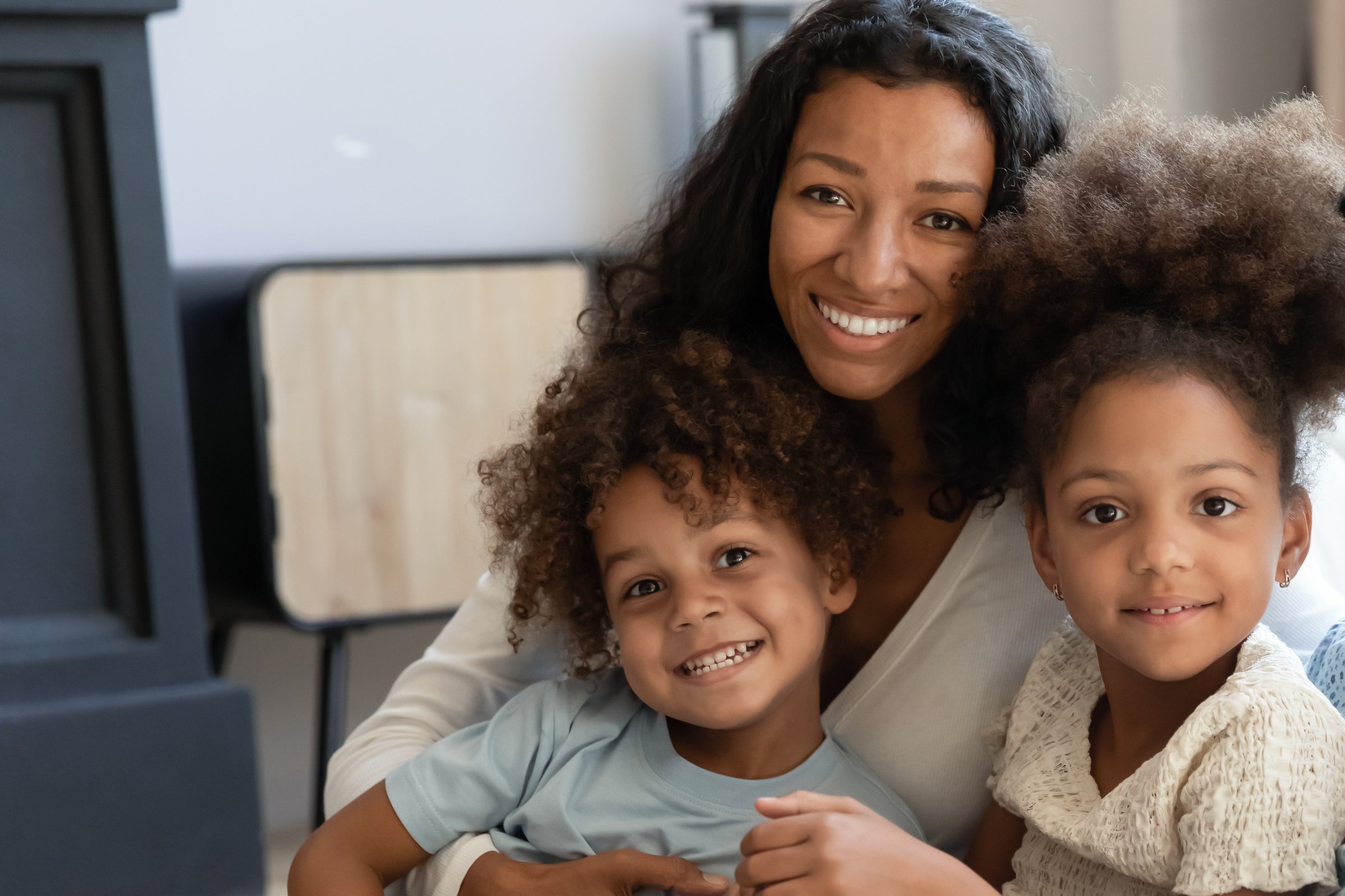 Portrait of happy African mother and two diverse children, smiling together as a close-knit family.