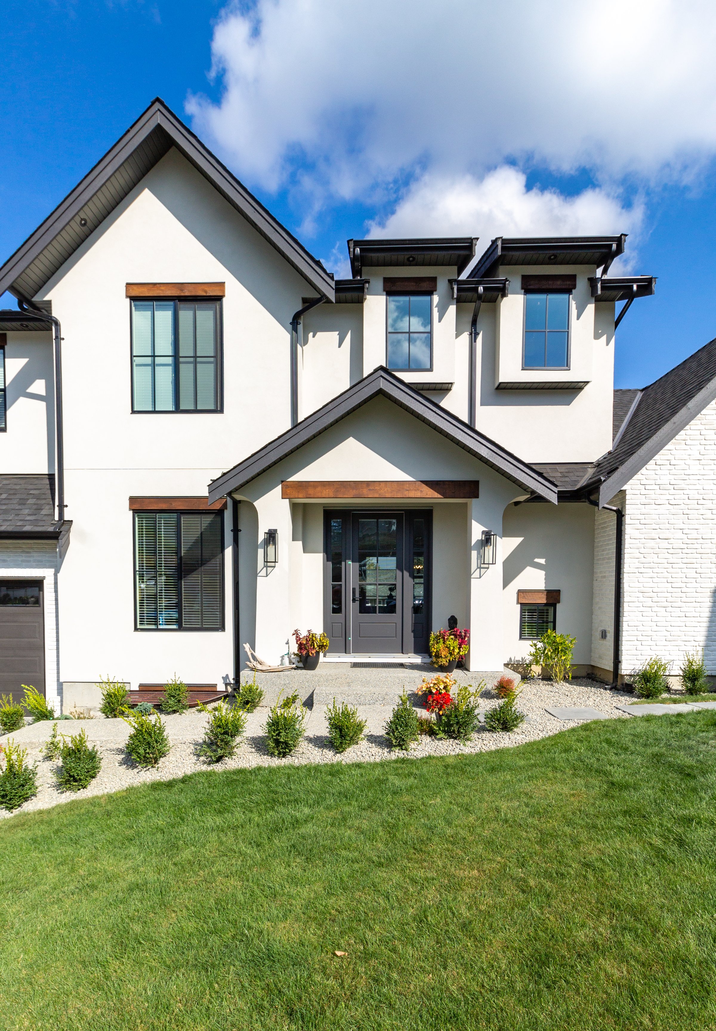 Front view of luxury two garage home with luscious green grass  on a blue sky day.