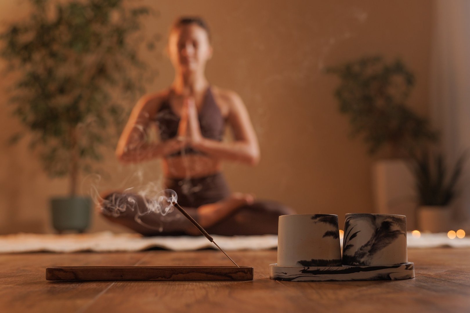 woman burning aroma stick for meditation and yoga in cozy warm atmosphere of room