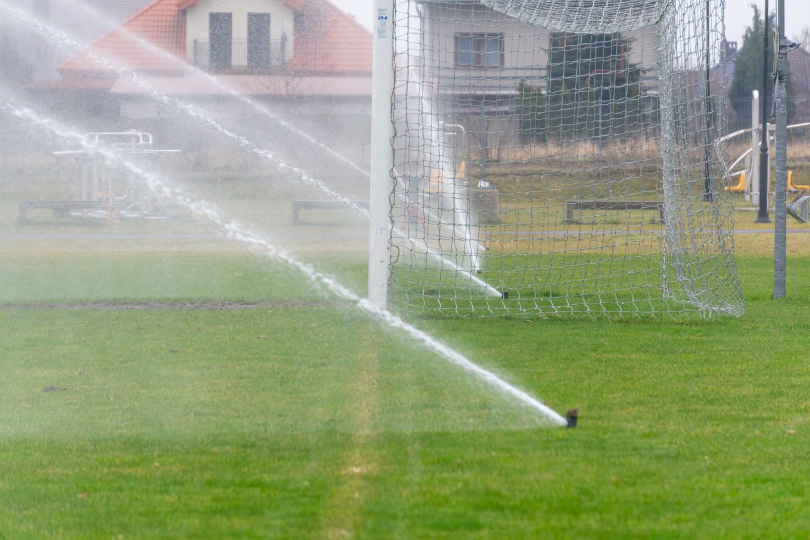 garden sprinklers spray water onto the pitch. grass irrigation systems during droughts. spraying water mist on a hot day.