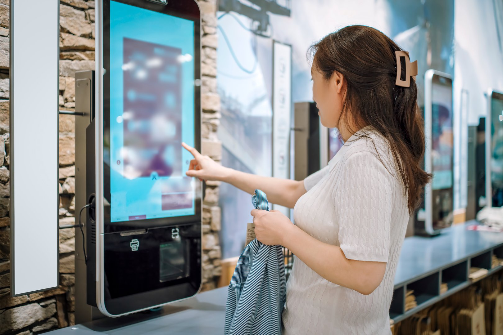A woman interacting with a self-service kiosk in a store