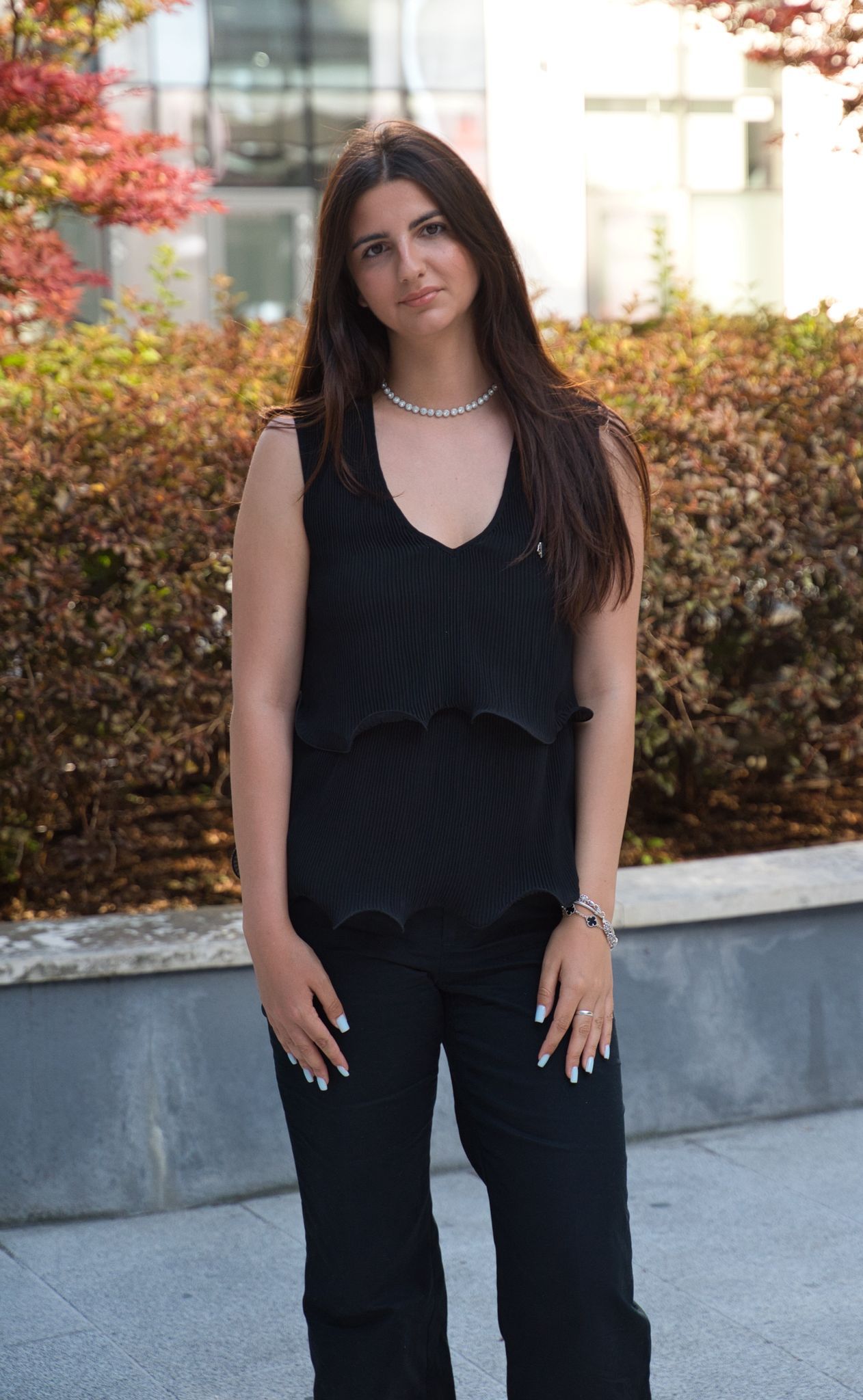 Woman with long hair in black top poses in front of a large clock with visible gears.