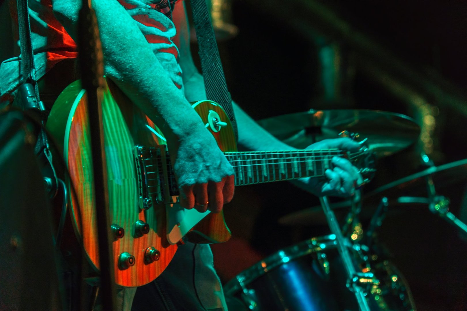 The guitarist plays on guitar in a dark room. Hands of a Guitar player playing the guitar. Low key