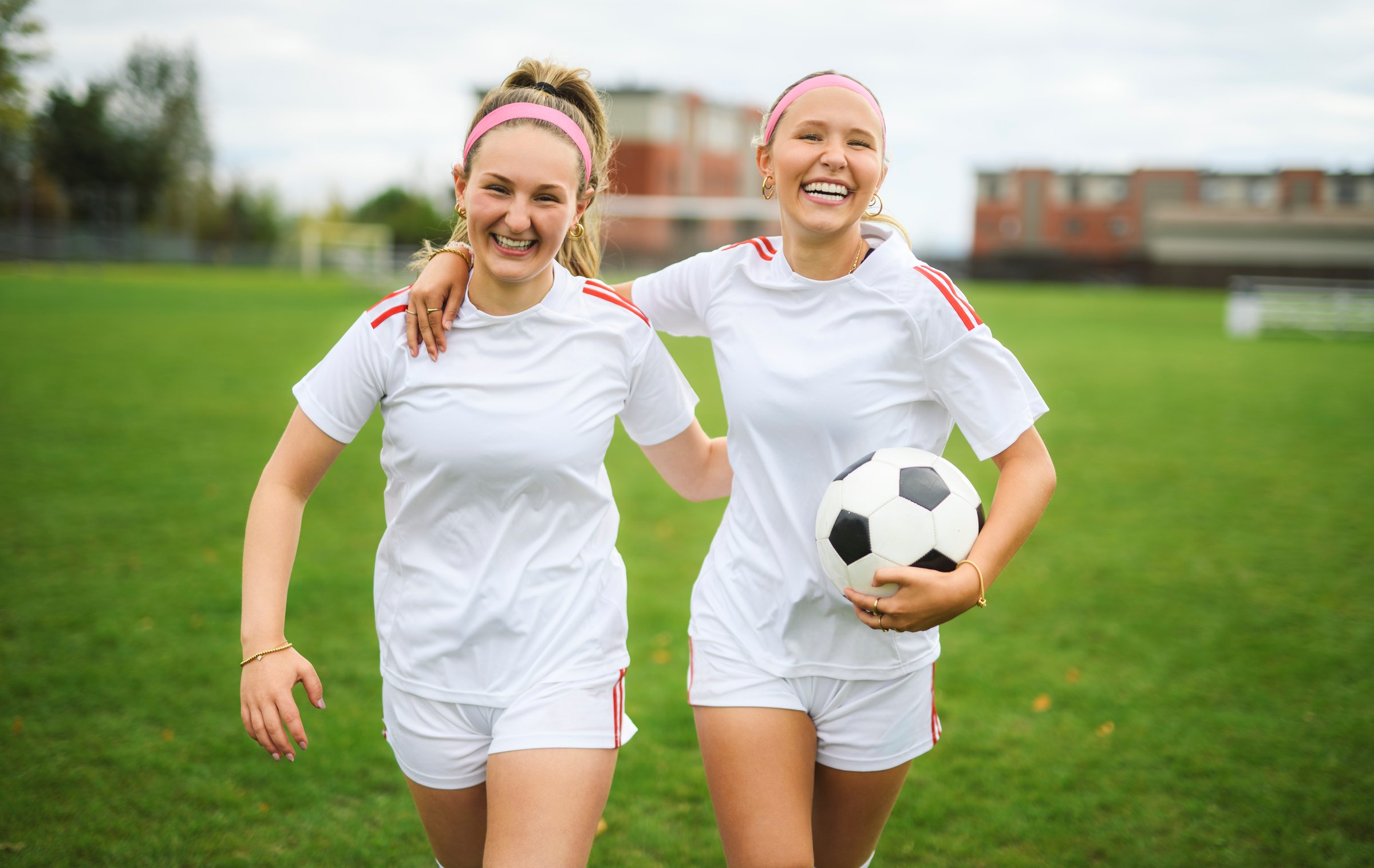 The two soccer player friends with a football in a sport uniform wearing in white