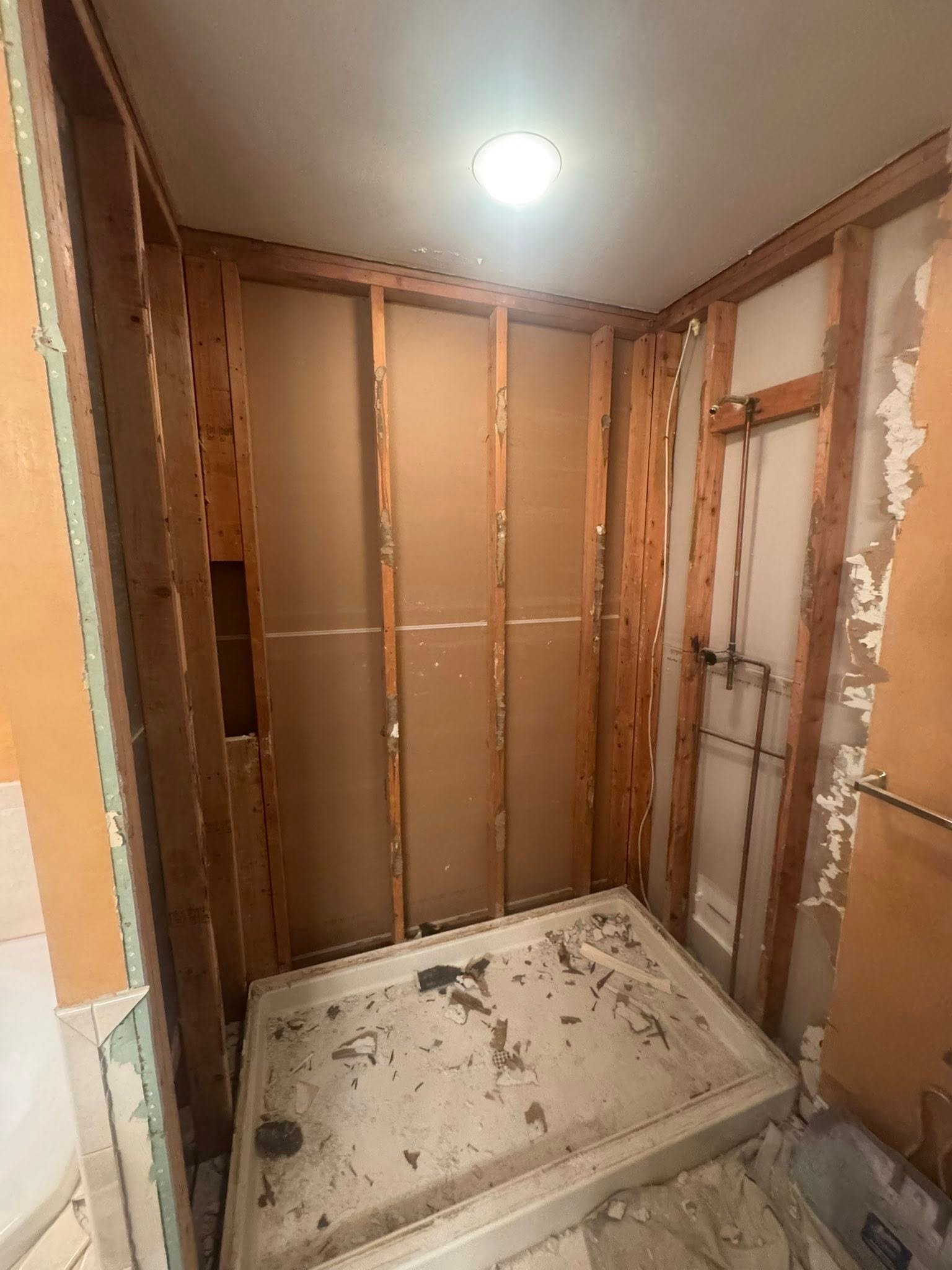Bathroom demolition revealing hidden water damage behind shower walls