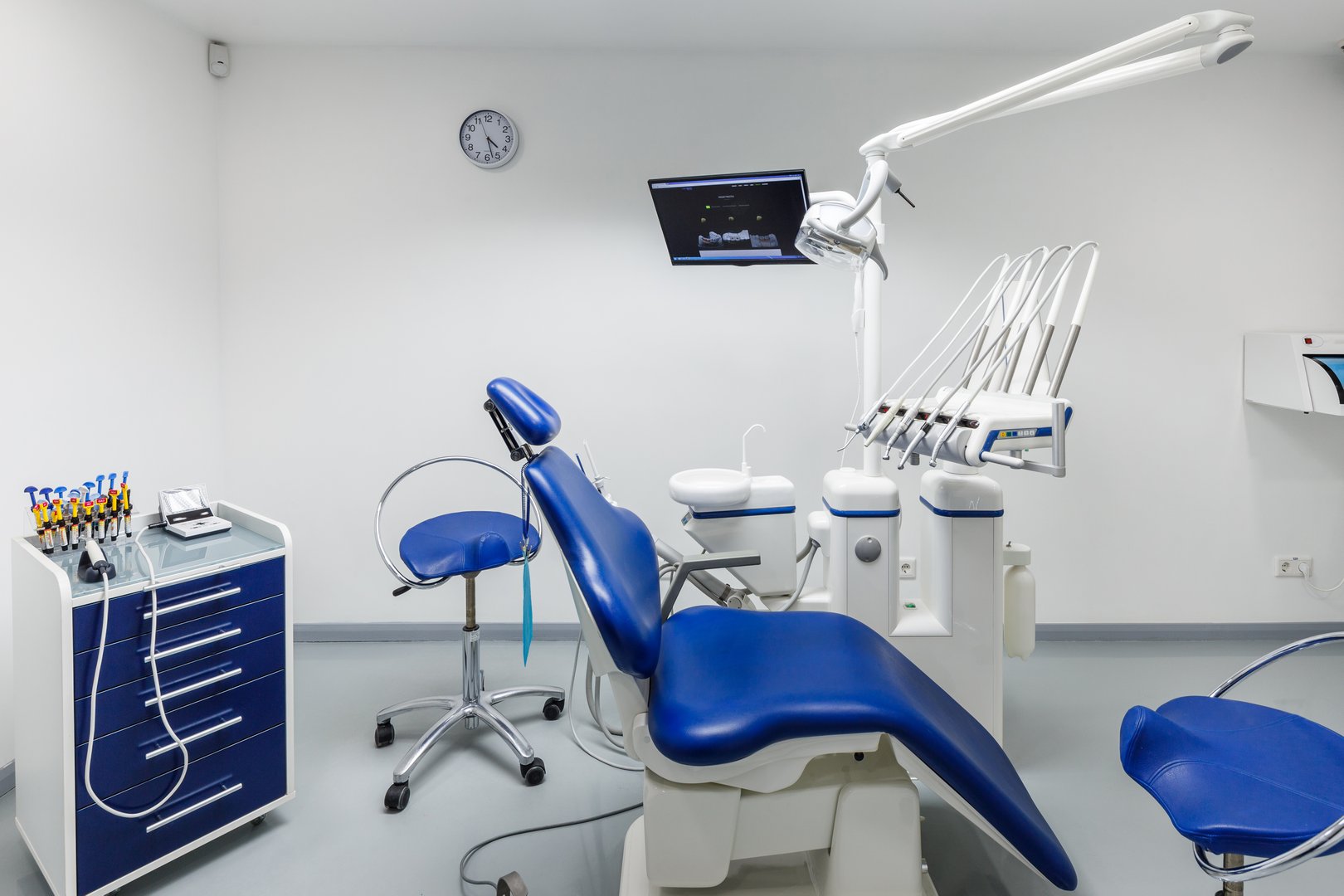 This image showcases a contemporary dental office setting featuring a blue treatment chair, organized tools, and high-tech apparatus, emphasizing hygiene and patient comfort.