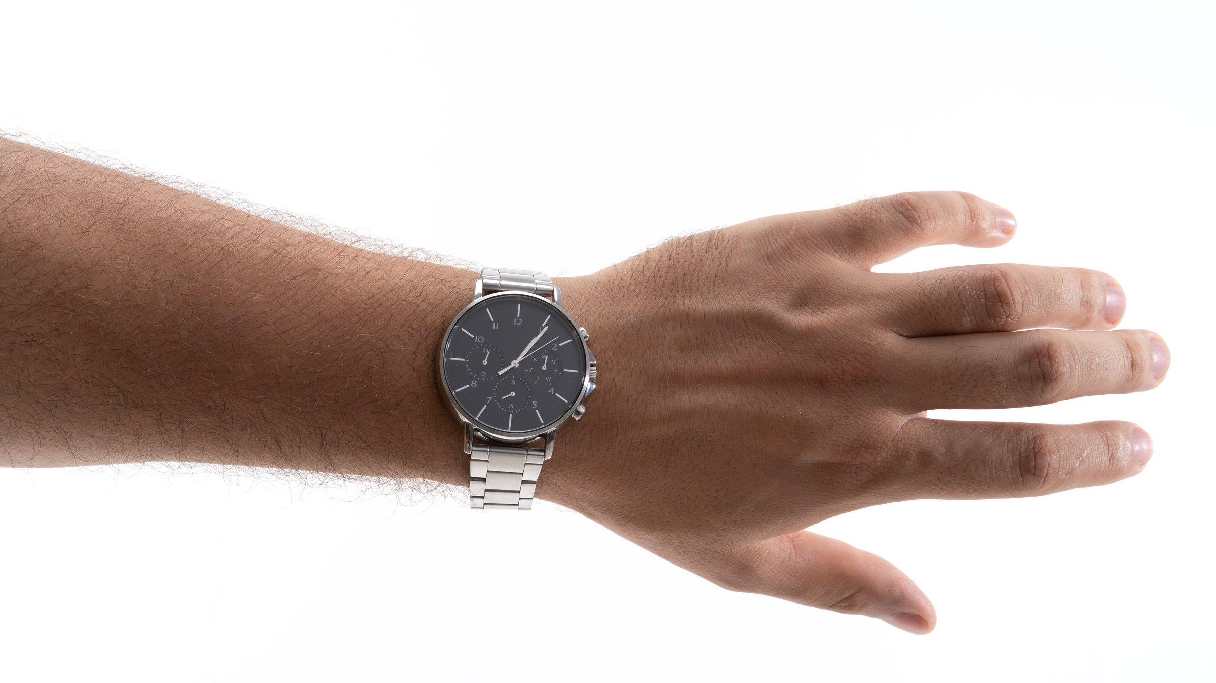 A hand extends outward, showcasing a sleek silver wristwatch with a black face. The bright background enhances the watch's elegant design and structure.