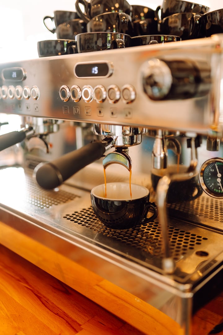 Espresso machine brews coffee and hot coffee pours into mug. Cozy coffee shop prepares aromatic drink for customers. Drink concept, barista and coffee shop. Small business.