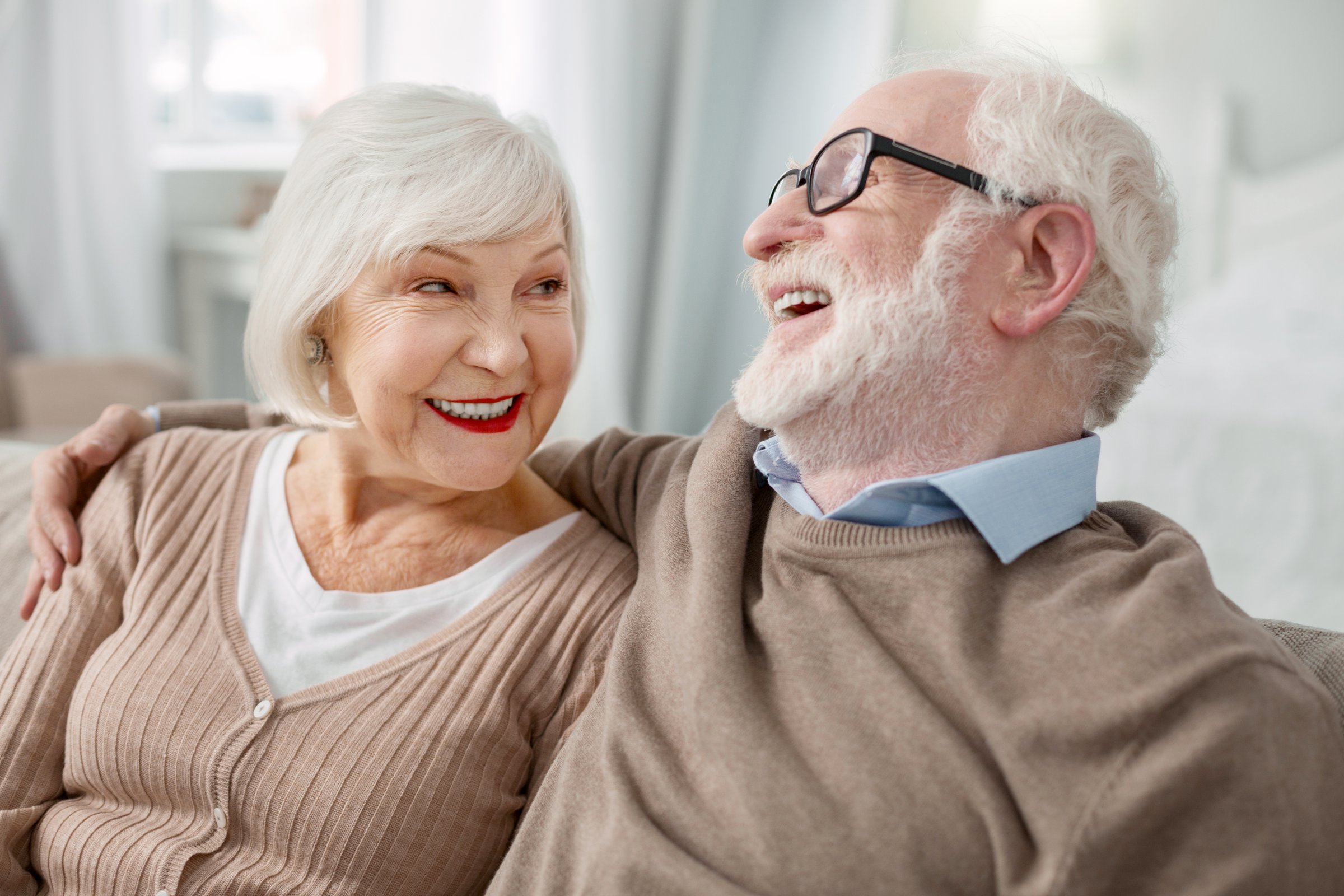 Elderly couple. Cheerful elderly man sitting together with his wife while hugging her