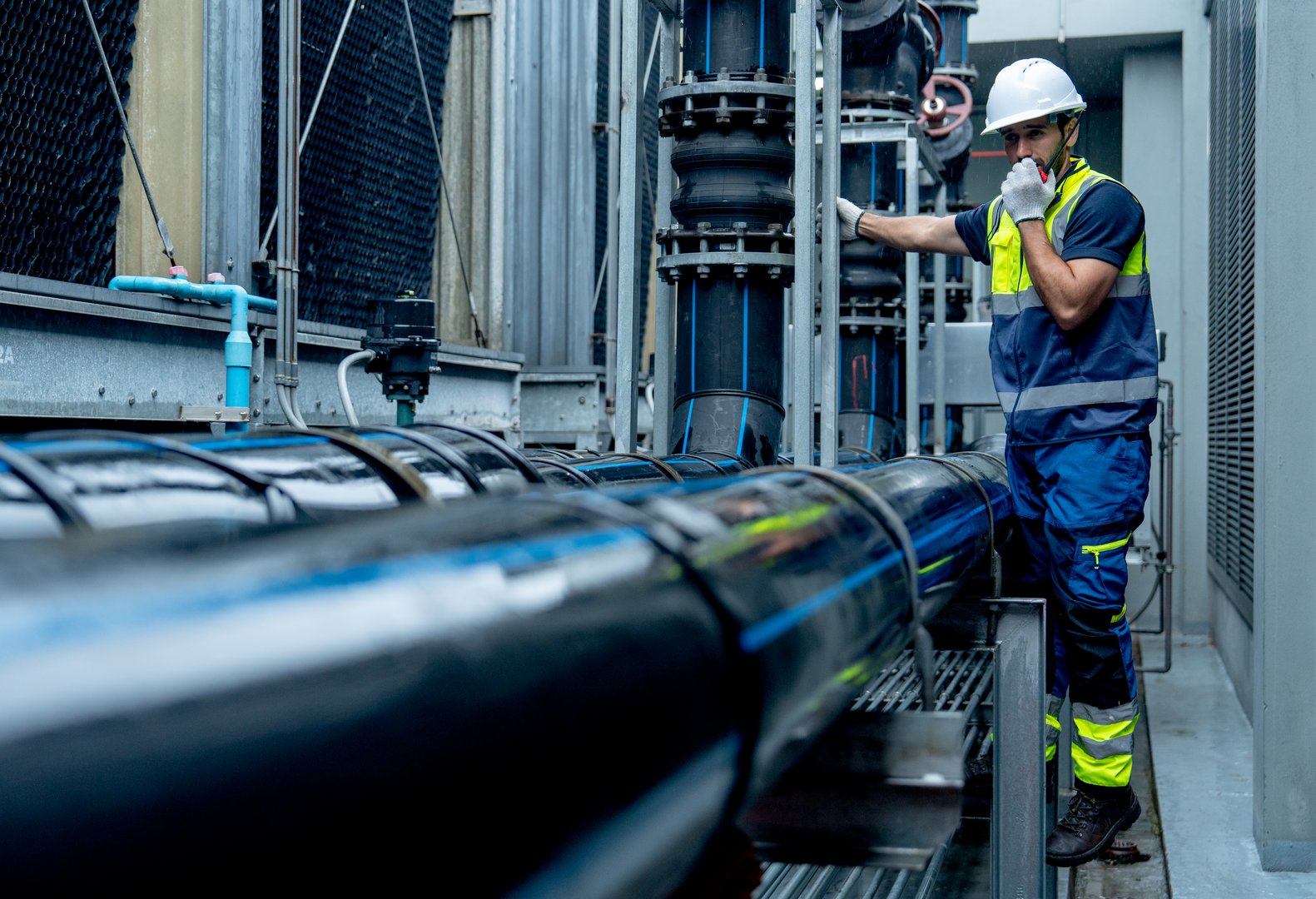 Engineer or technician worker use walkie talkie to contact co-worker  during work with temperature controling pipe system of factory building.