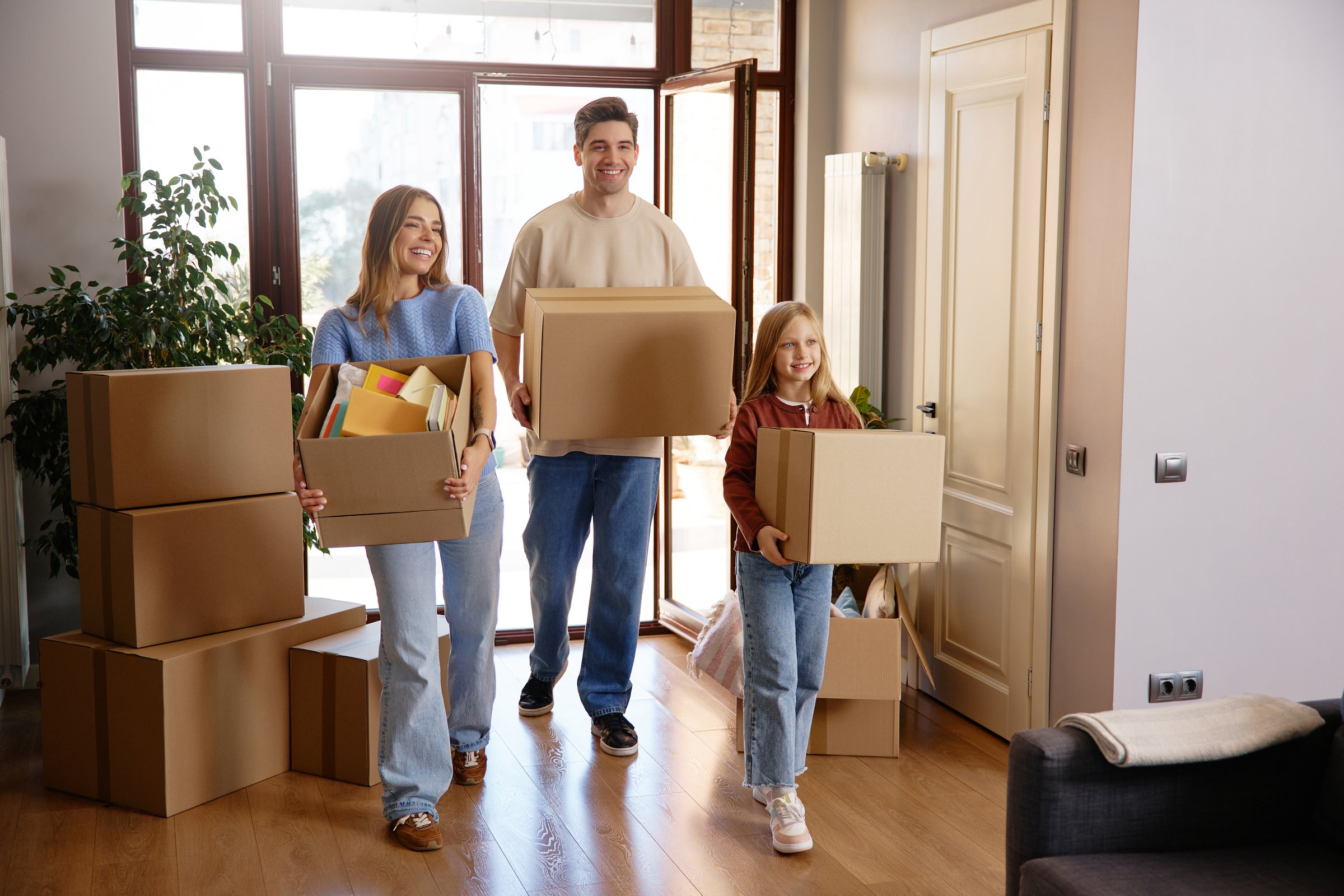 Cheerful family of three with cardboard boxes during house moving