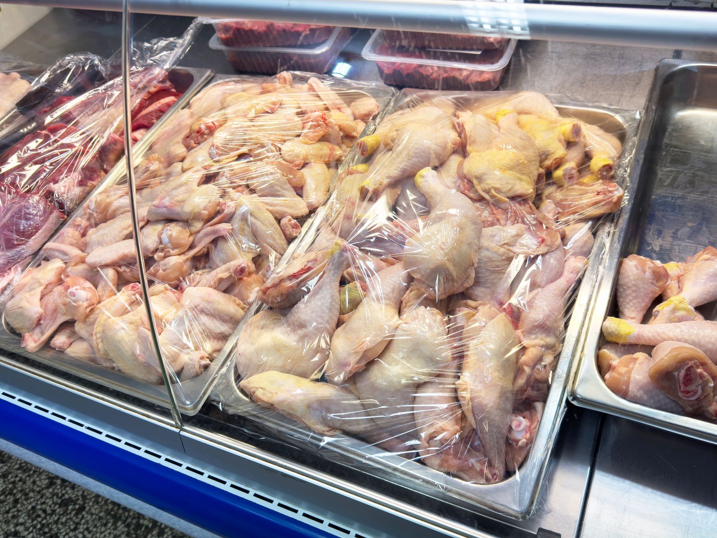 Fresh raw chicken displayed in butcher shop counter, lifestyle