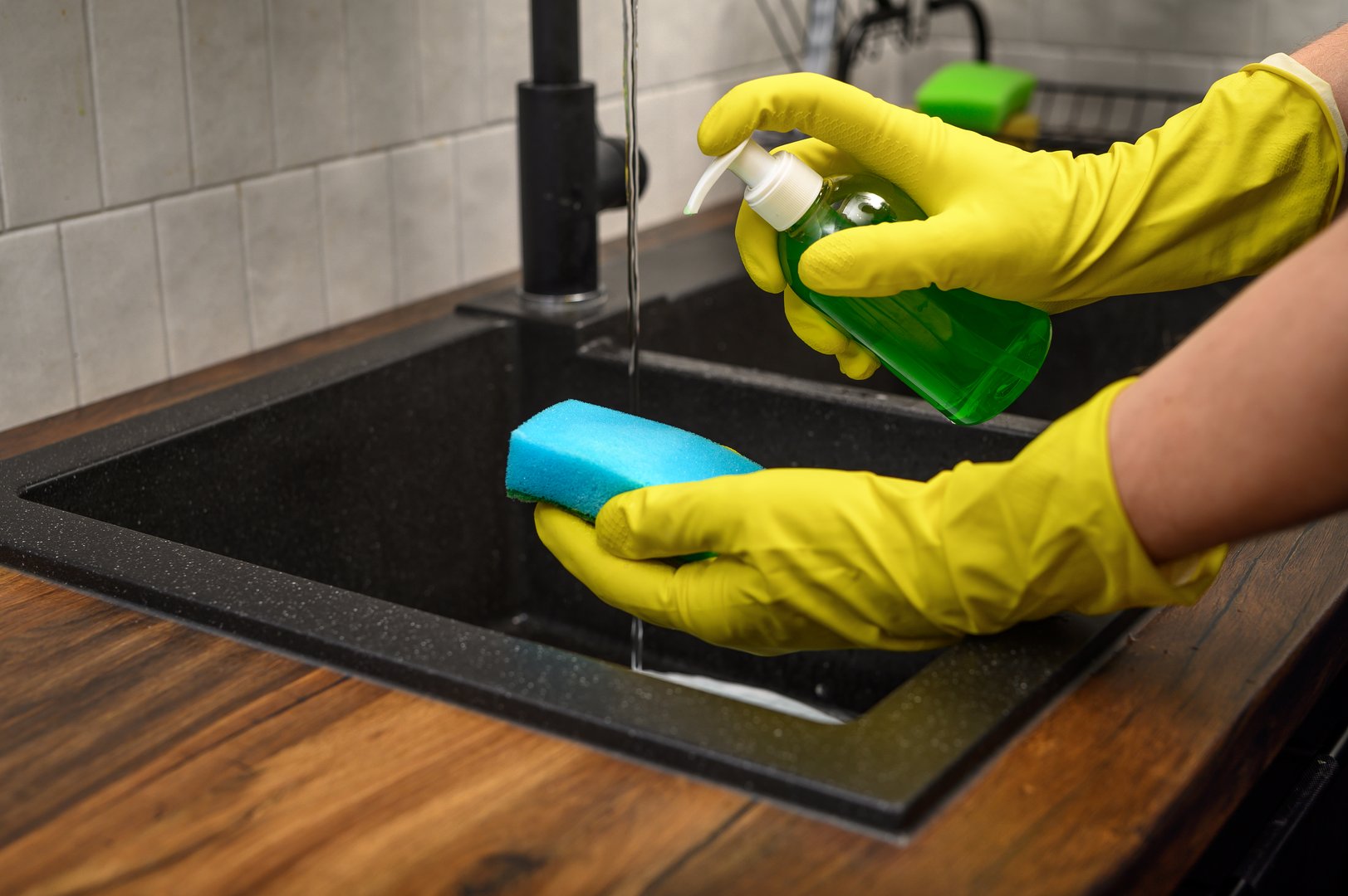 Washing dishes wearing rubber protective gloves