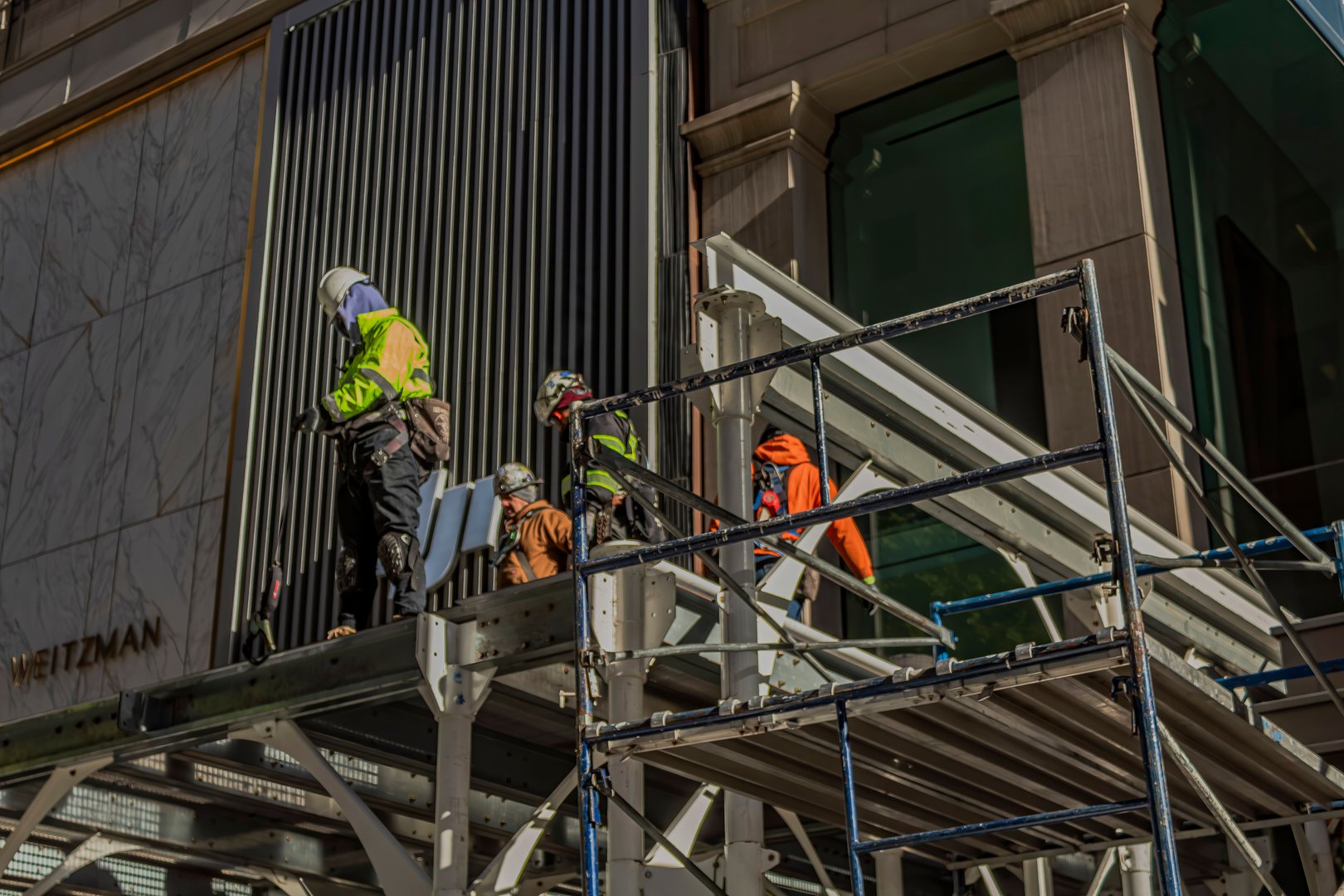 New York, United States – November 13, 2024: Construction workers assembling scaffolding in front of a skyscraper on Fifth Avenue, NYC, on a sunny day.