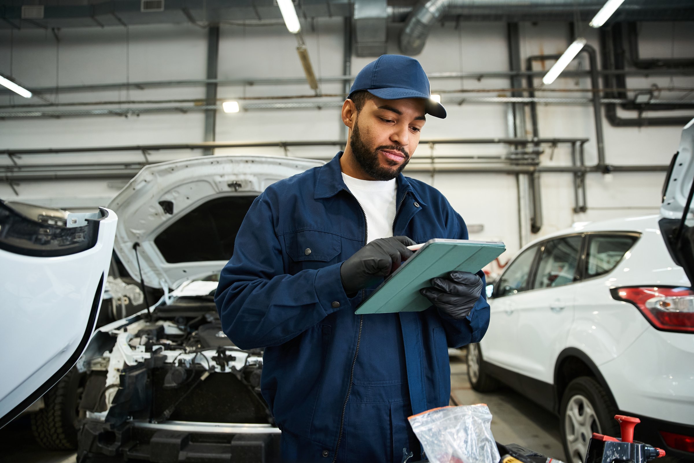 A young mechanic reviews car maintenance tasks while working at a repair service center.