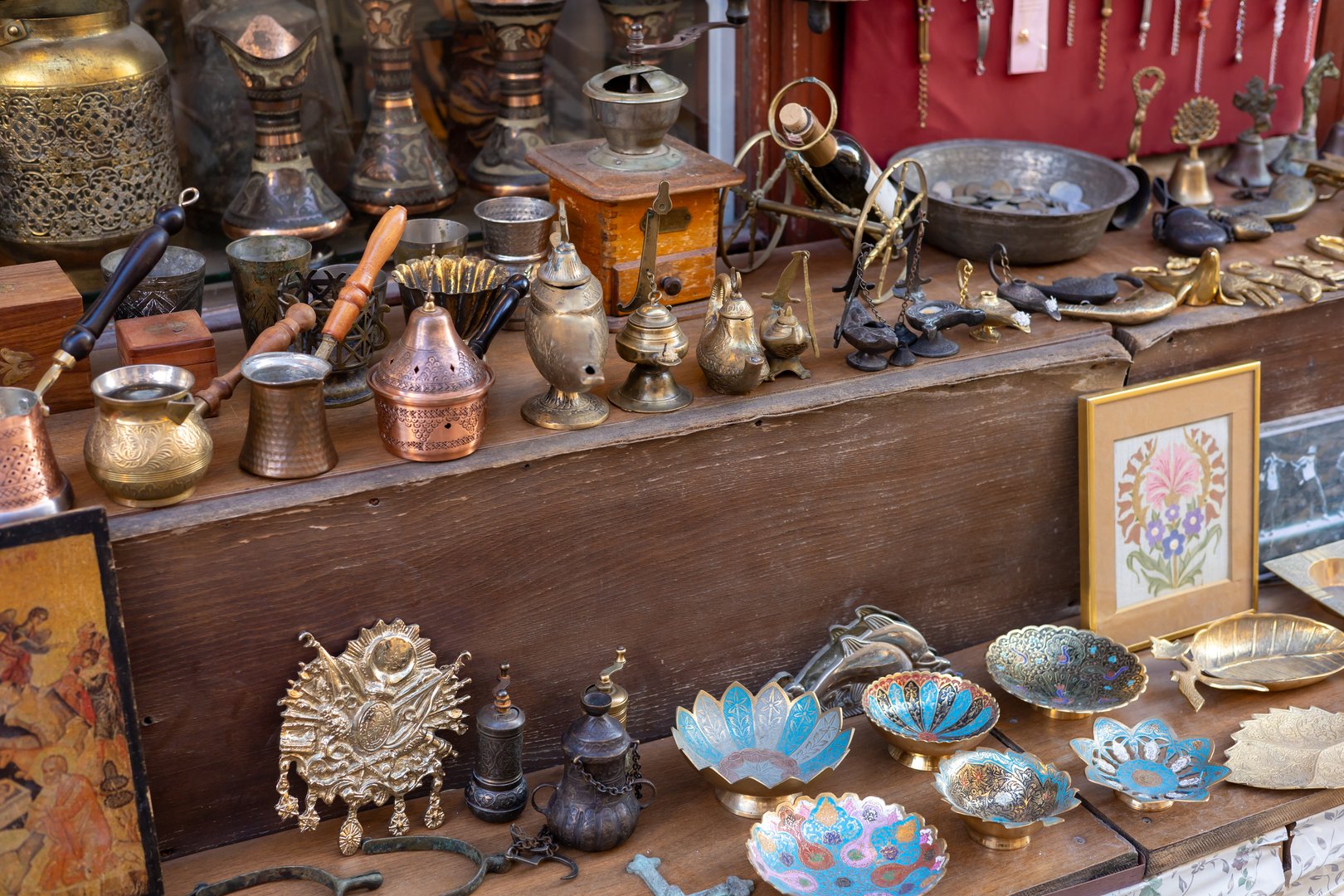 Antalya, Turkey - September 30, 2024: An assortment of beautifully crafted brass and copper items is laid out on a wooden table at a bustling market stall. Various artisanal pieces, including bowls, pots, and decorative trinkets, showcase intricate designs and craftsmanship, capturing the vibrant essence of the local culture during the lively evening hours.
