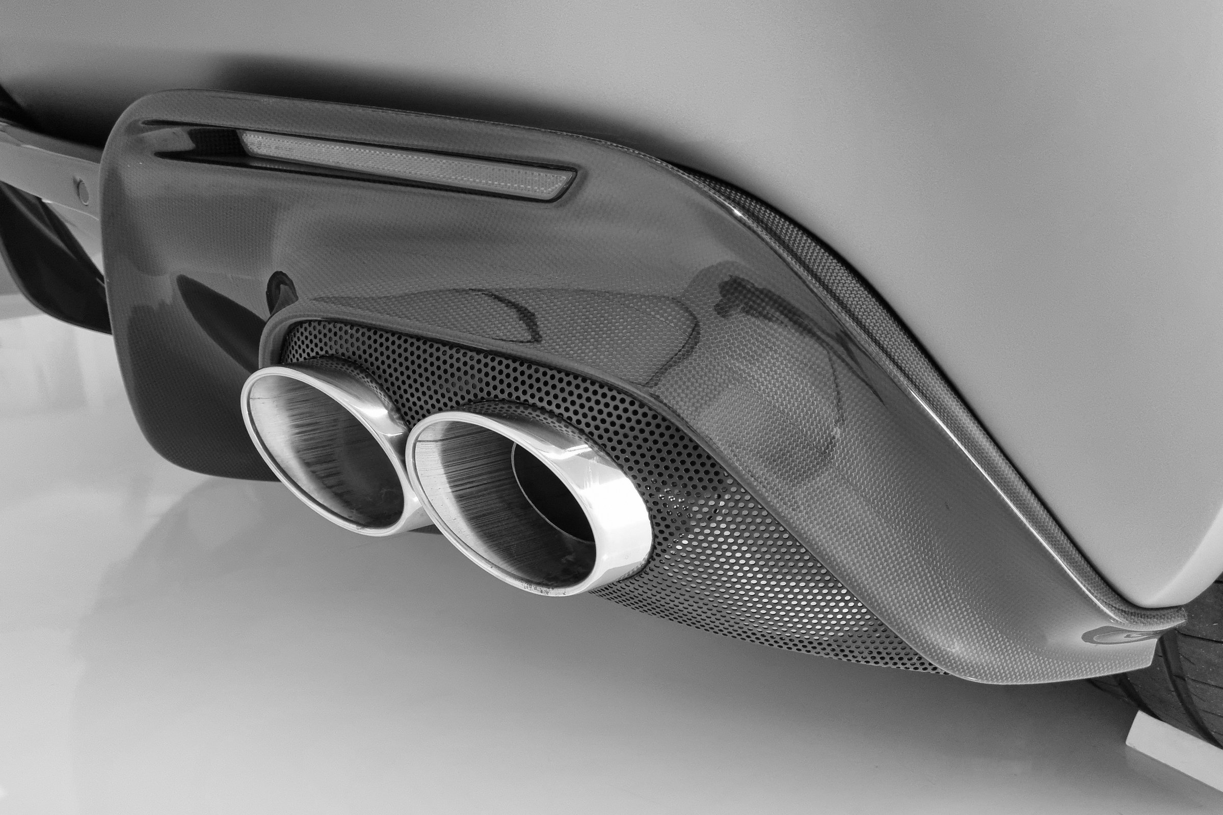 Close-up of a dual exhaust system on a sports car, captured in black and white. the modern design and sleek lines highlight the advanced automotive engineering and aesthetic detail, perfect for use in automotive design projects, prints, and posters.