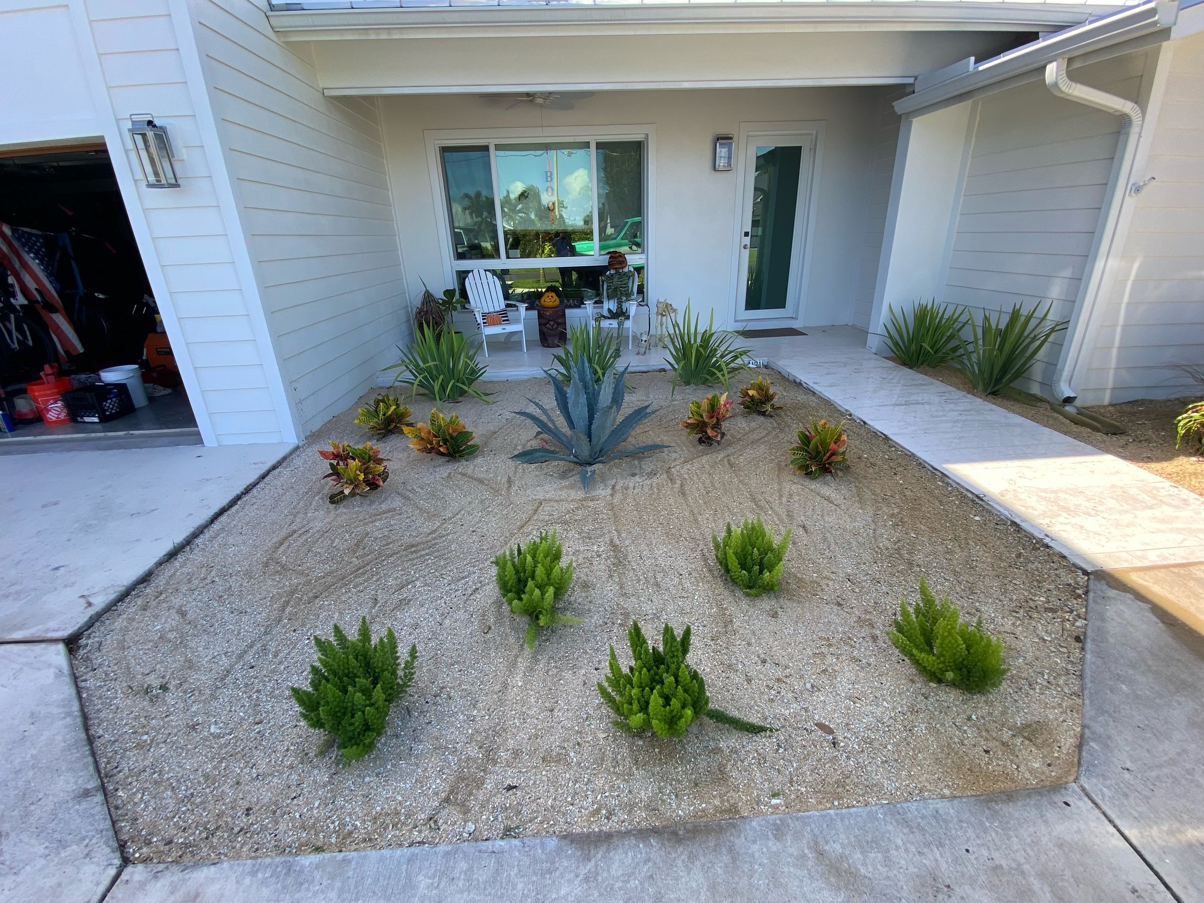 A modern house entrance with a minimalist desert garden featuring succulents and a central agave plant.