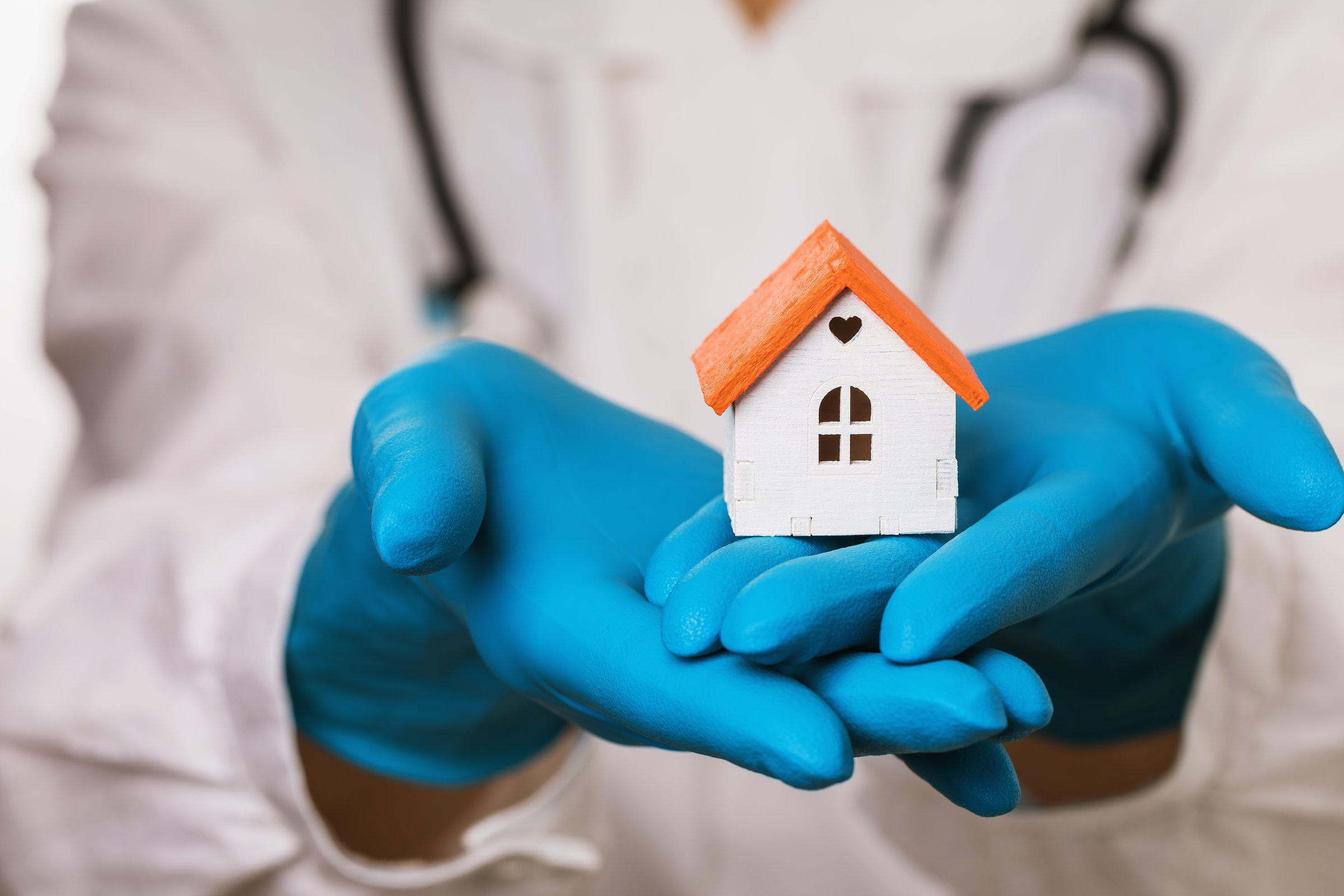 The doctor holds in his hands a toy house, symbolizing family health