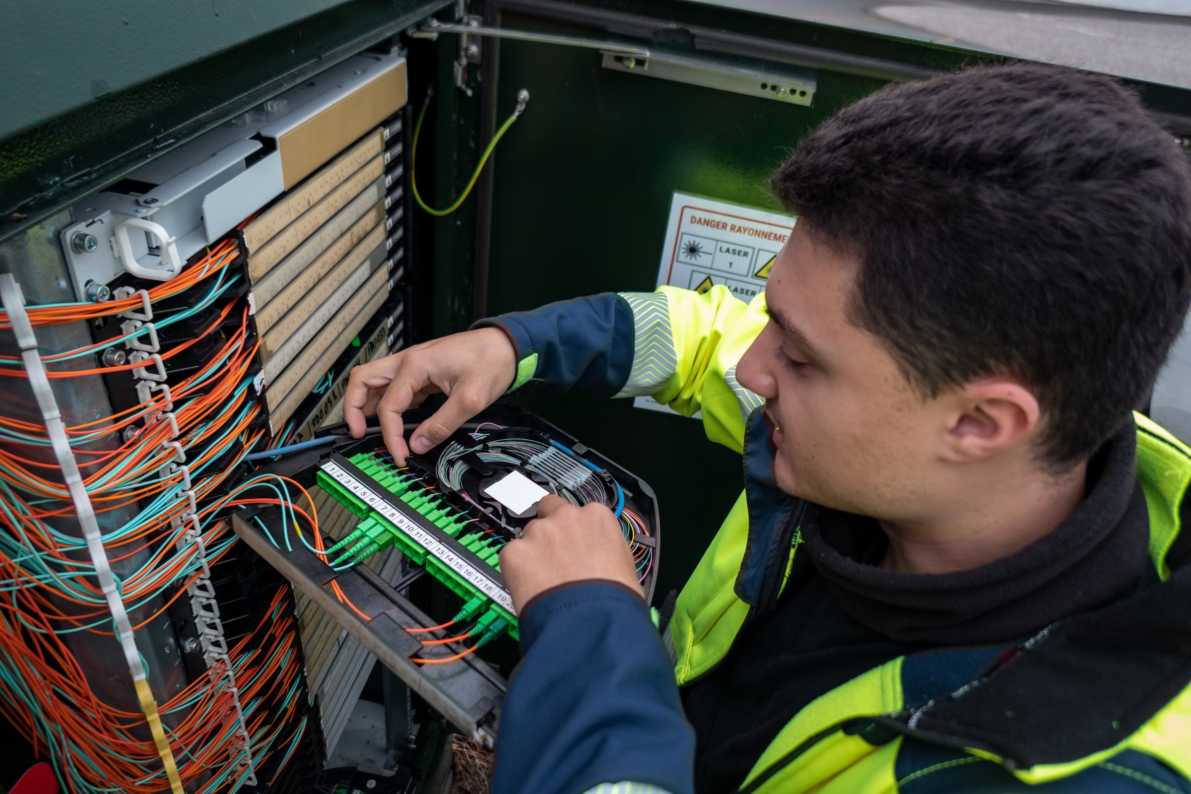 Fiber optic technician performing repairs on a cabinet to restore network access to customers affected by the failure