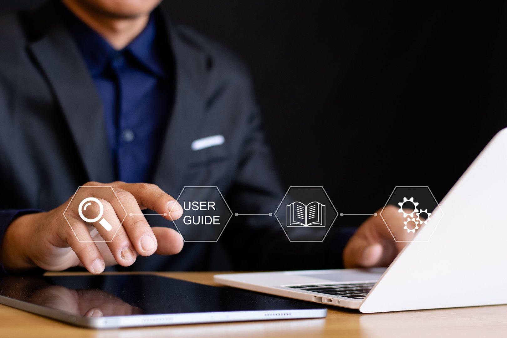 Businessman using laptop with virtual user manual icon for business services, online manuals and strategy guides.
