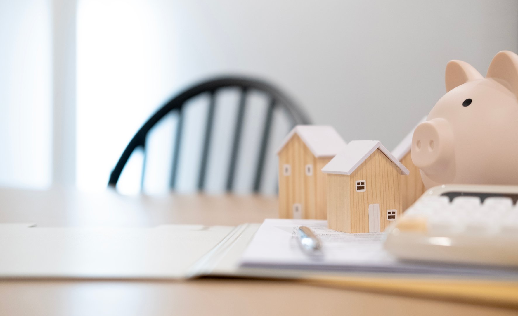 Piggy bank with wooden house models, illustrating real estate savings, property investment, home ownership goals, and future housing plans. Concepts about home purchase planning and installment