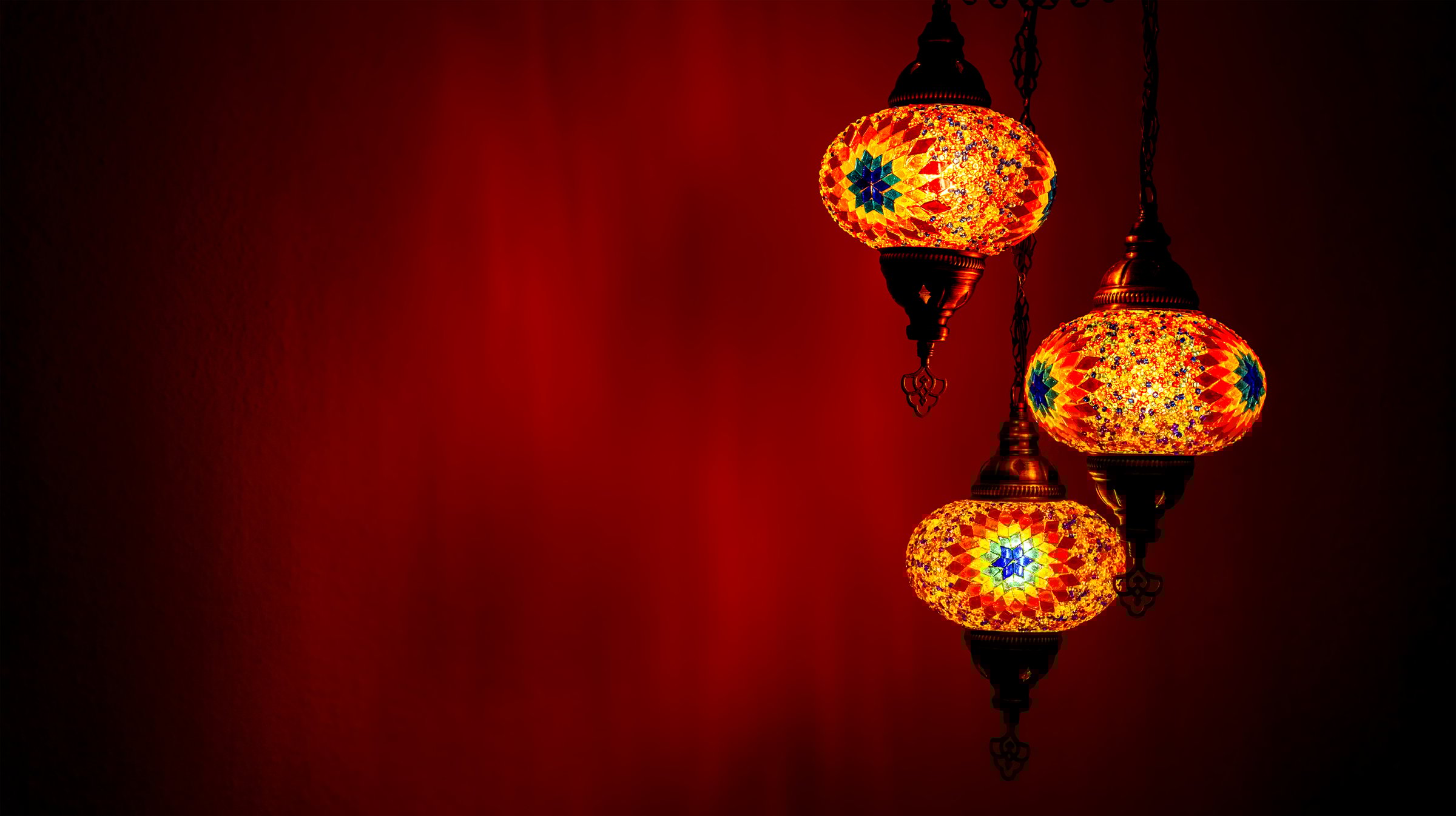Colourful Turkish lamps with three lamps hanging over. The handmade glass design sparkles in the night light