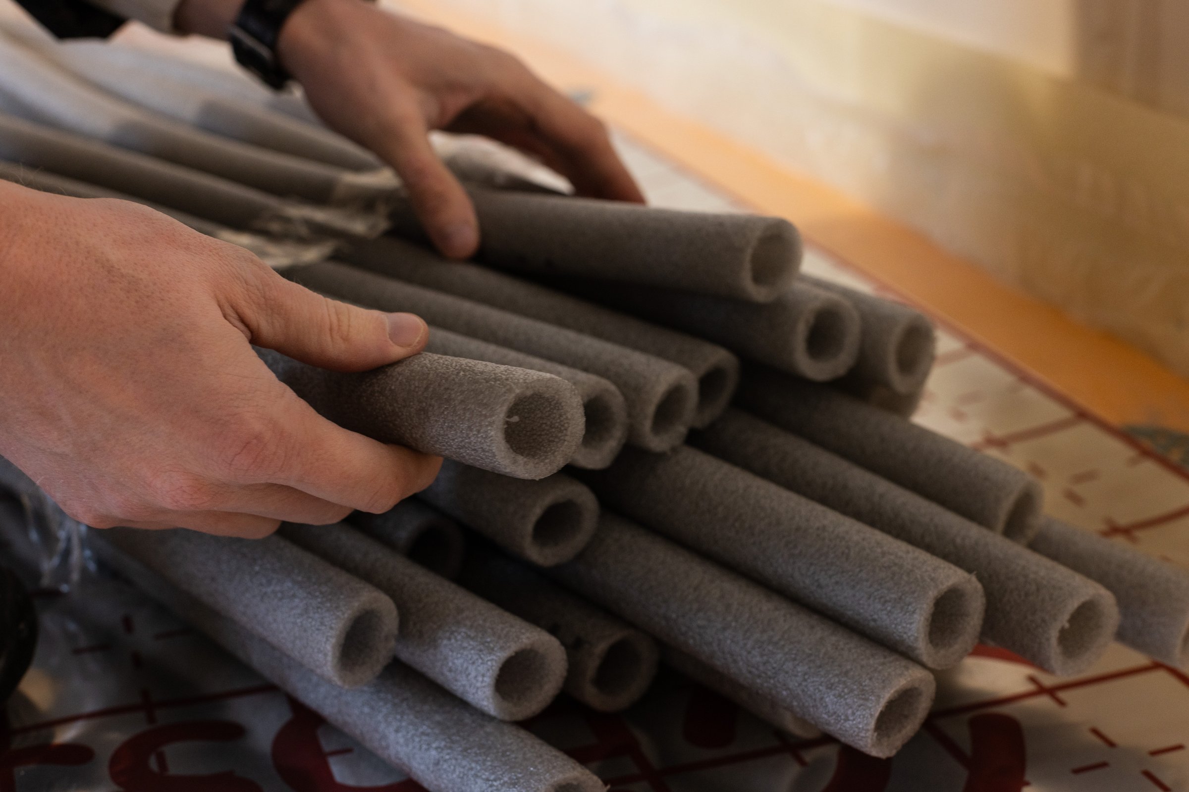 Man holding grey soft isolation for pipes of the water supply and heating system. Closeup, selective focus